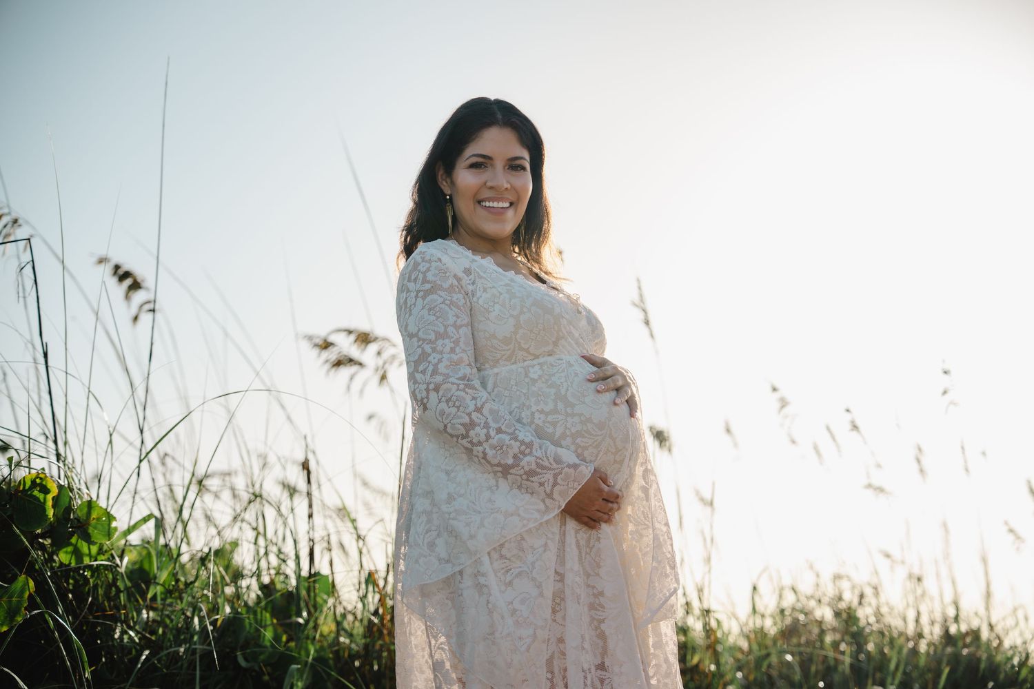 Maternity session in Dania Beach with woman in lace dress smiling in the dunes