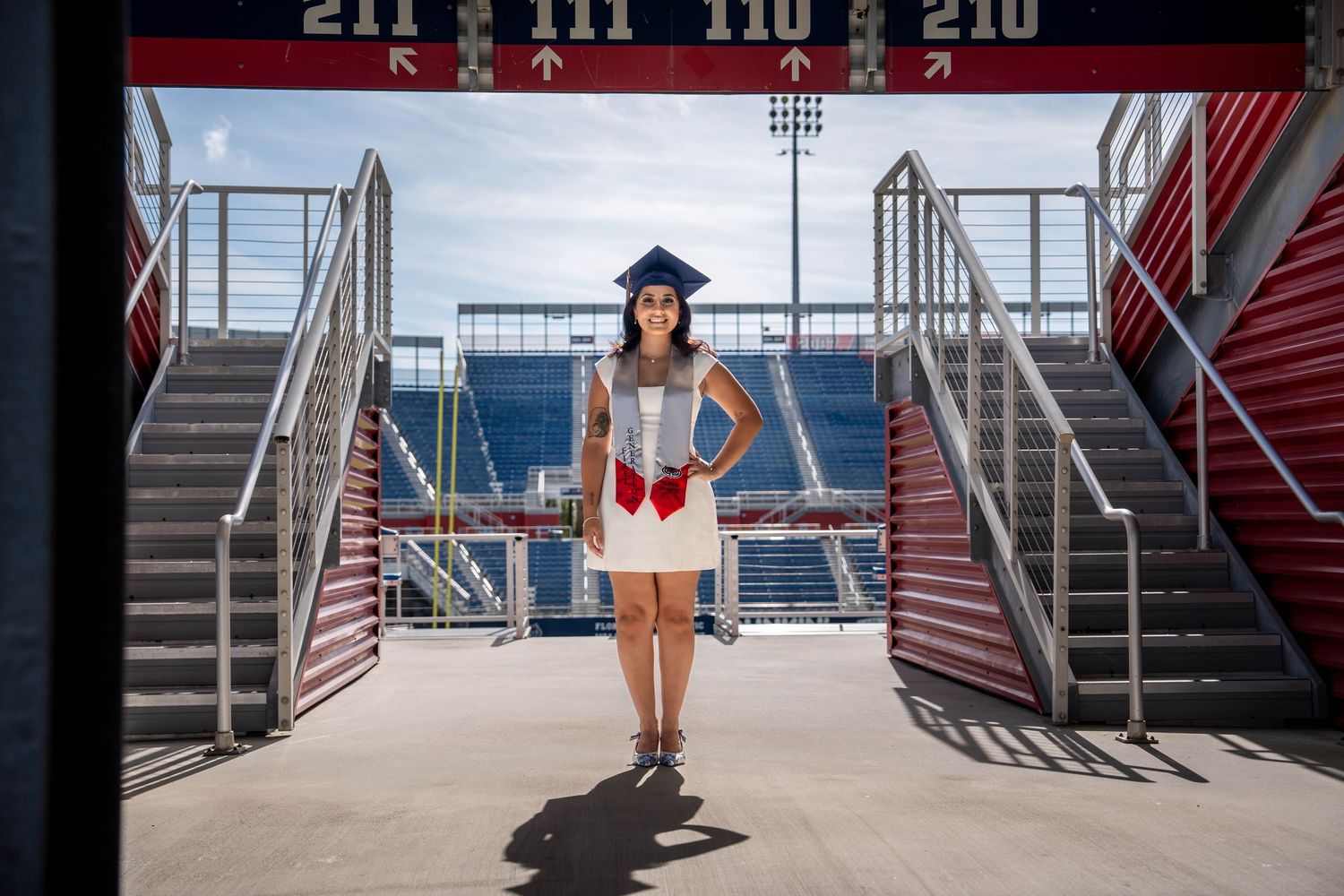 Graduation portrait of FAU student smiling on stadium balcony in Boca Raton