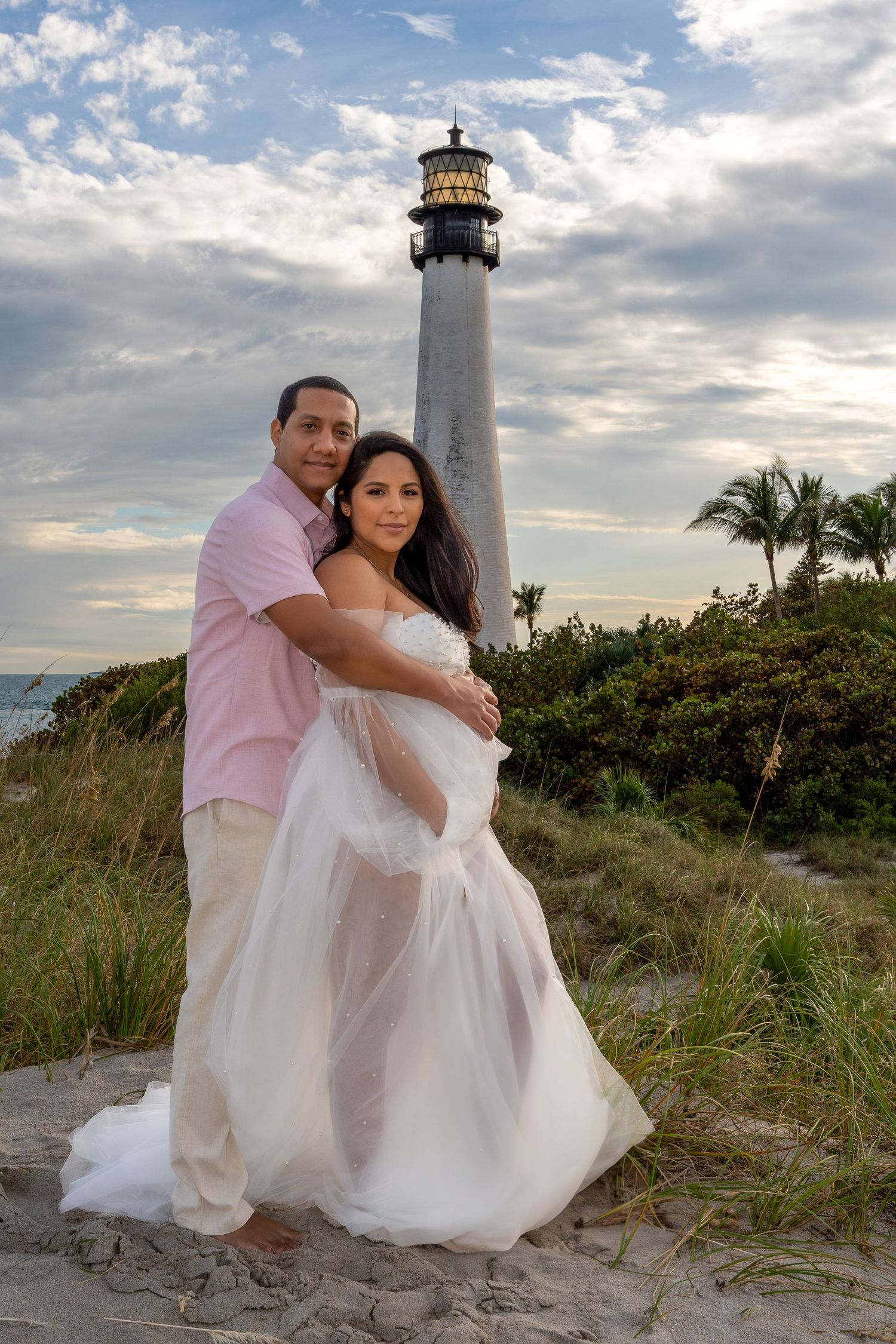 Romantic maternity session at Cape Florida Lighthouse with soft sunset light, celebrating a couple’s journey into parenthood.