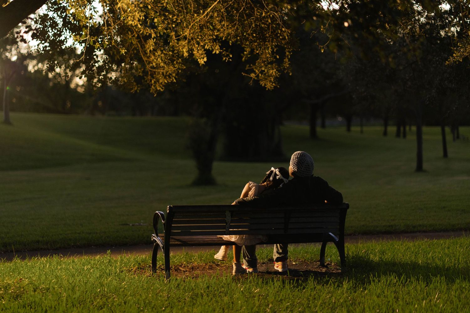 Romantic couple enjoying a quiet sunset moment on a park bench in Fort Lauderdale, FL, surrounded by lush greenery.