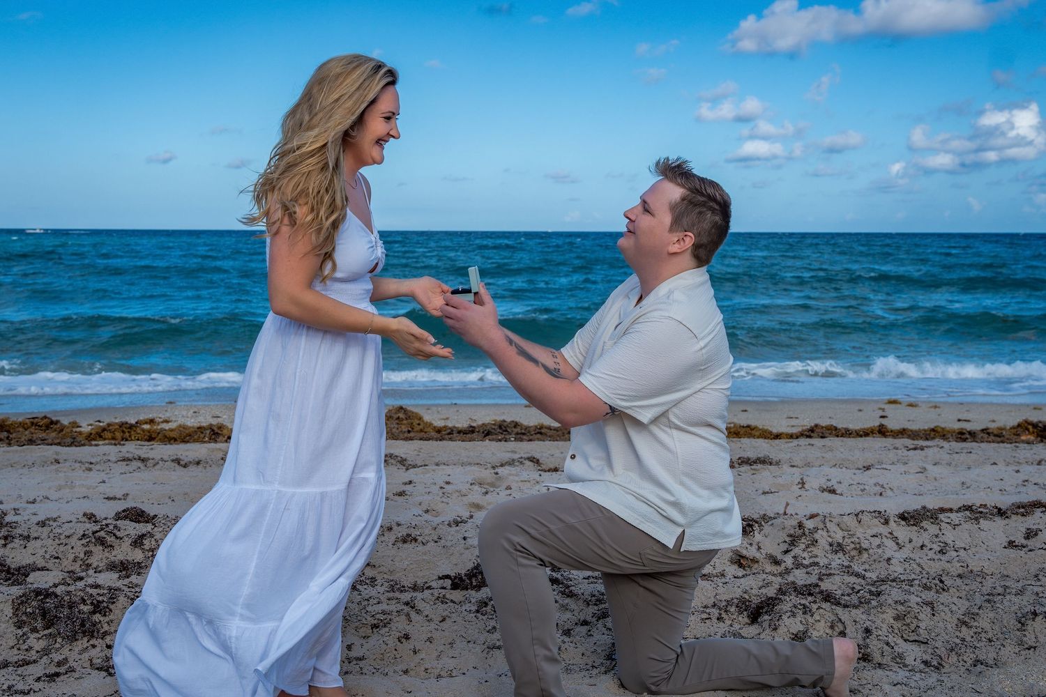 Scenic beach proposal in South Florida, capturing a once-in-a-lifetime moment with the ocean waves behind them. man on one knee