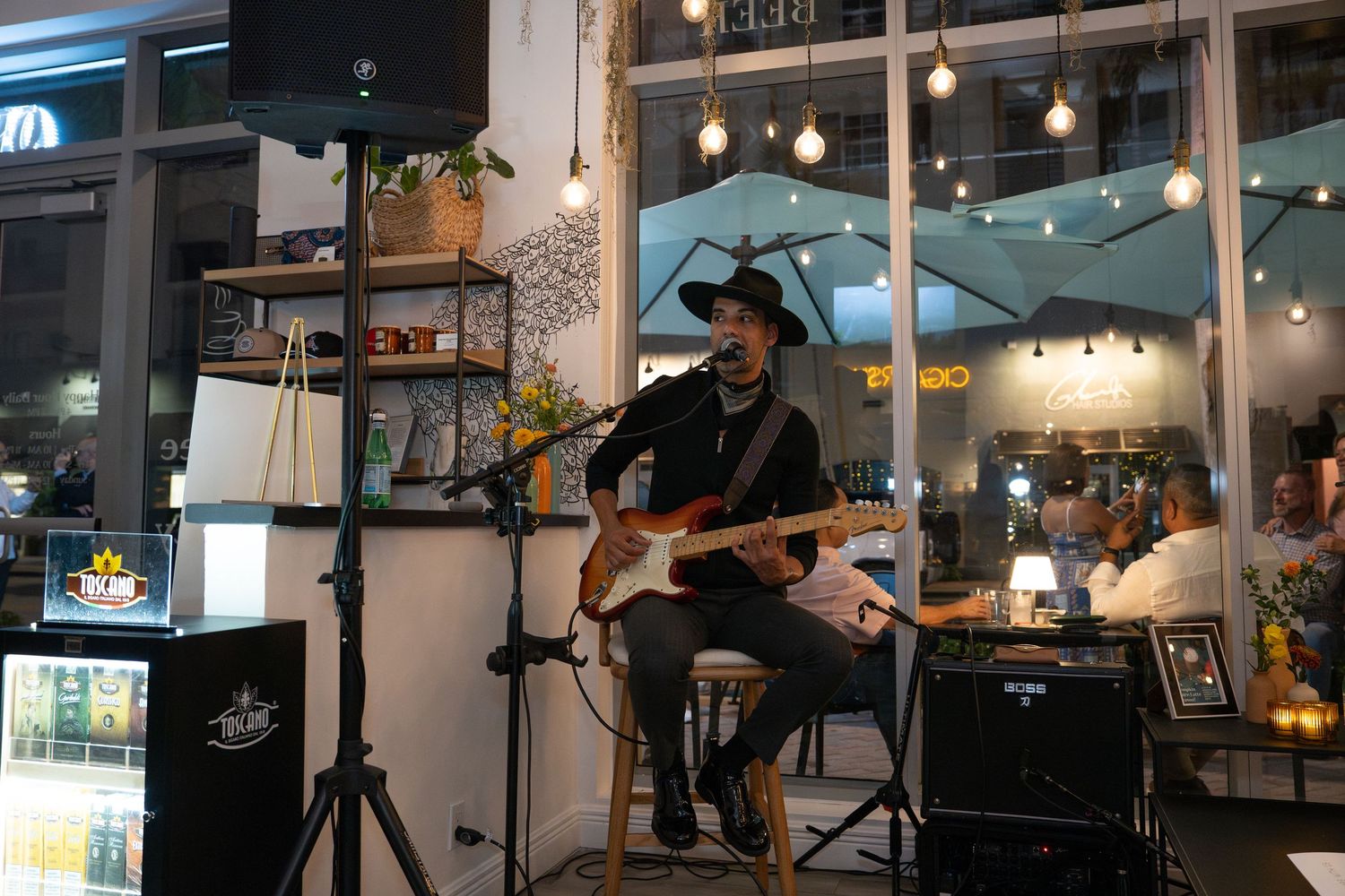 Live musician performing with a guitar inside Bartolo’s Wine Bar & Cigar Shop during the grand opening event.