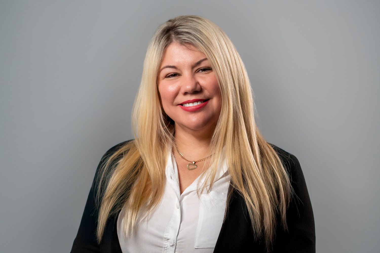 Blonde woman smiling during studio headshot session on gray background
