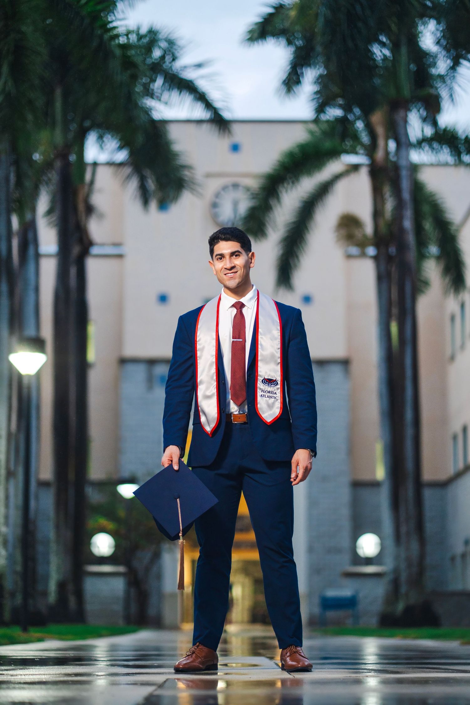 Florida Atlantic University graduation portrait of a graduate standing between palm trees on campus in Boca Raton.