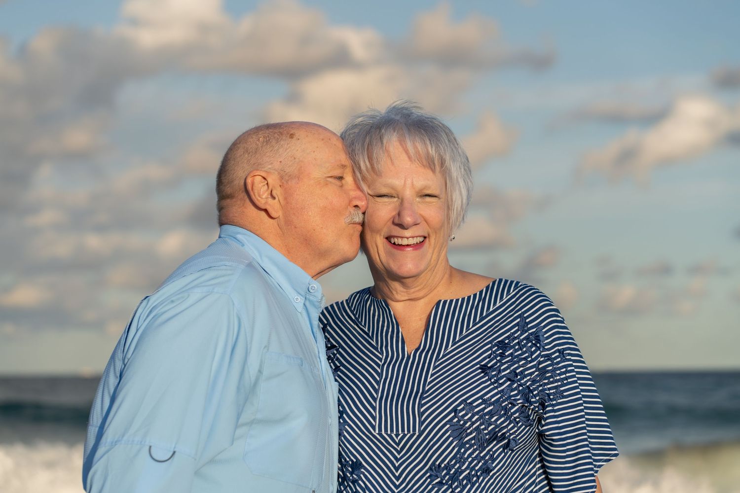 Golden hour beach portrait in Palm Beach, FL – elderly couple sharing a sweet moment with ocean waves in the background.