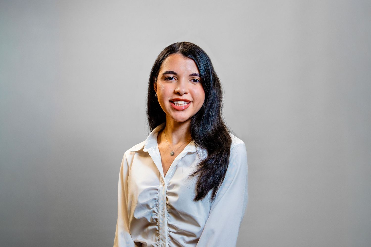 Professional headshot of female chiropractor against studio backdrop in South Florida