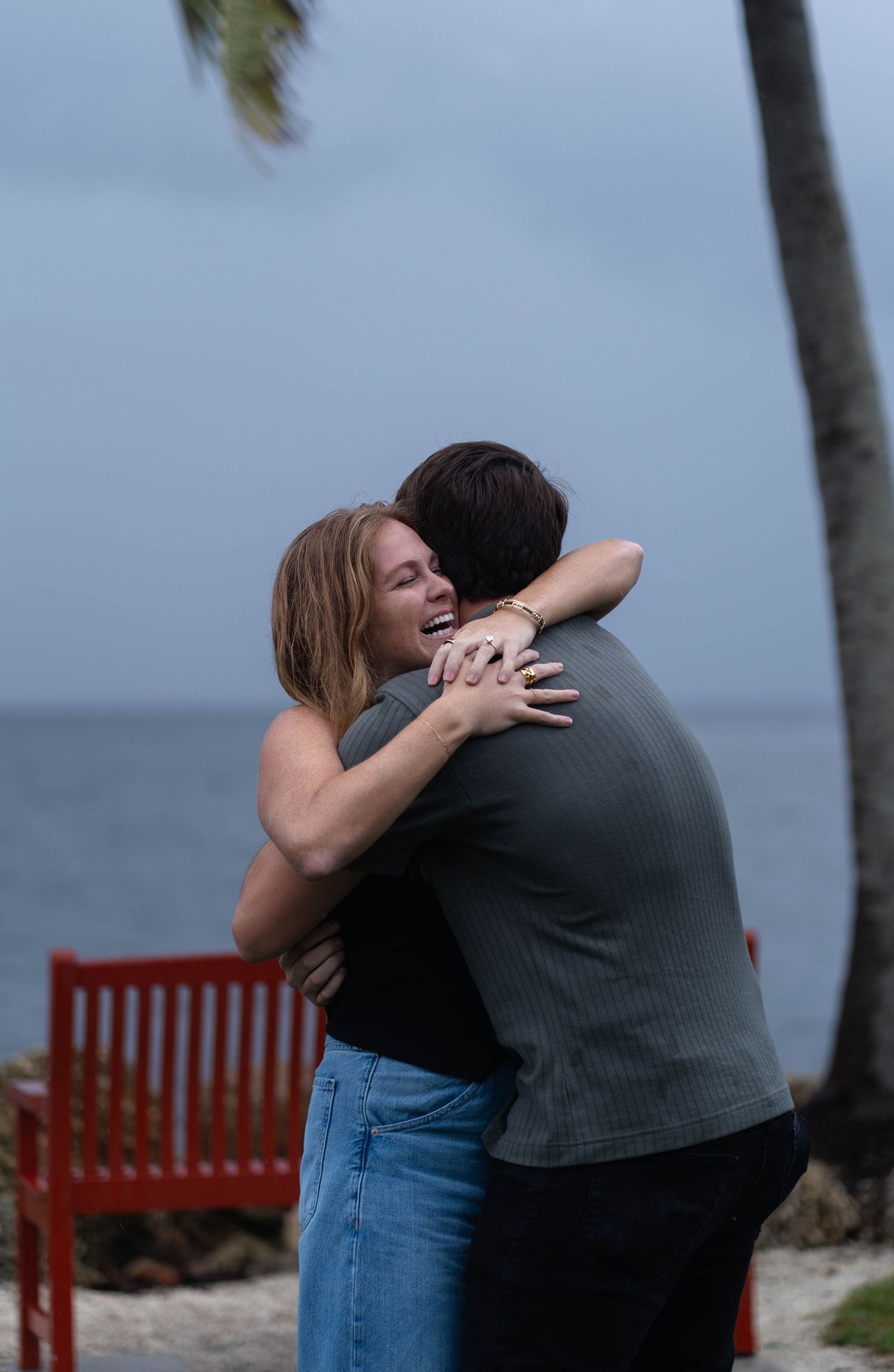 Emotional moment of a couple embracing during a surprise proposal by the water in South Florida Miami