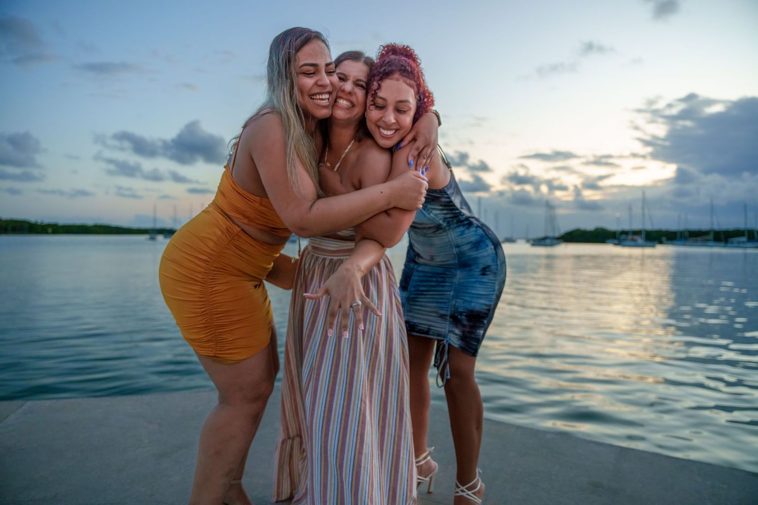 Celebratory photo of friends hugging and smiling after a proposal in Key Biscayne by the water.