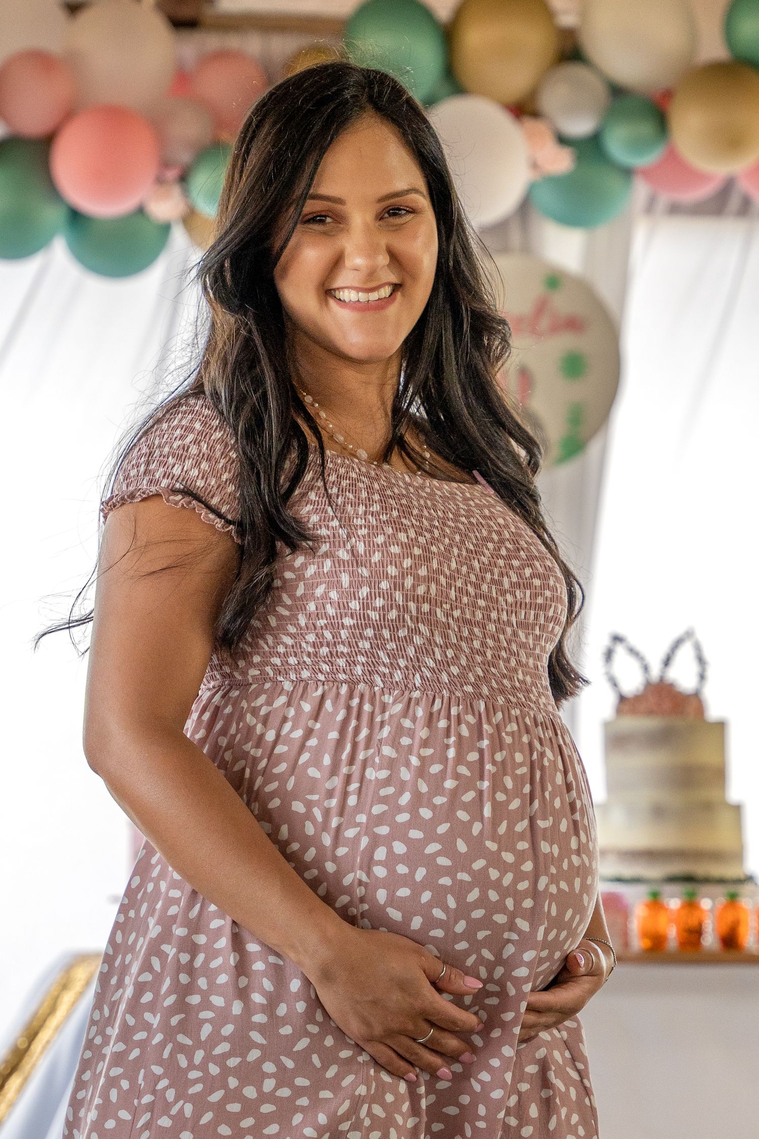 Portrait of an expecting mother smiling beside a dessert table at a South Florida baby shower.