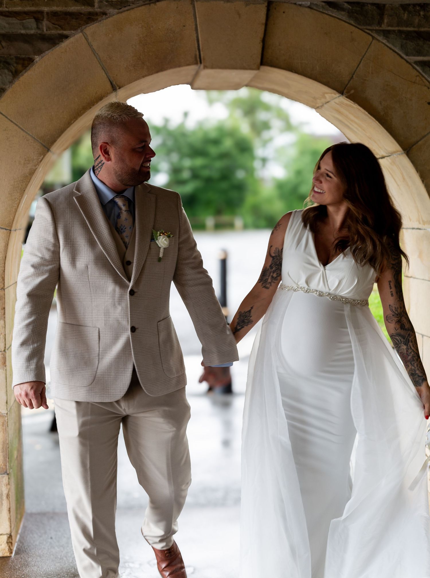 Wedding couple shares romantic moments under stone archway in sequence of elegant white attire photos.