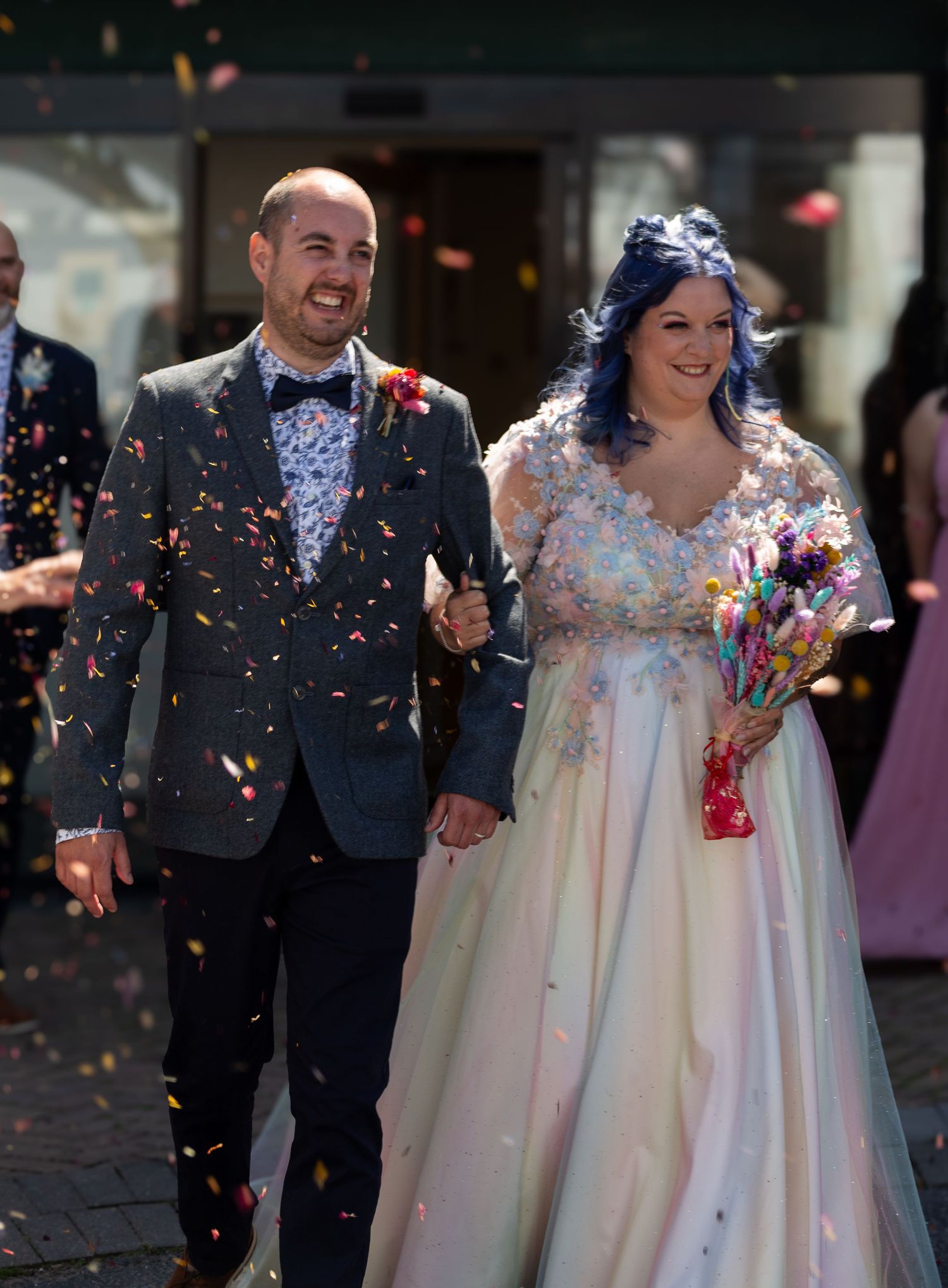 Newlywed couple walks together as colorful confetti rains down during their wedding celebration.