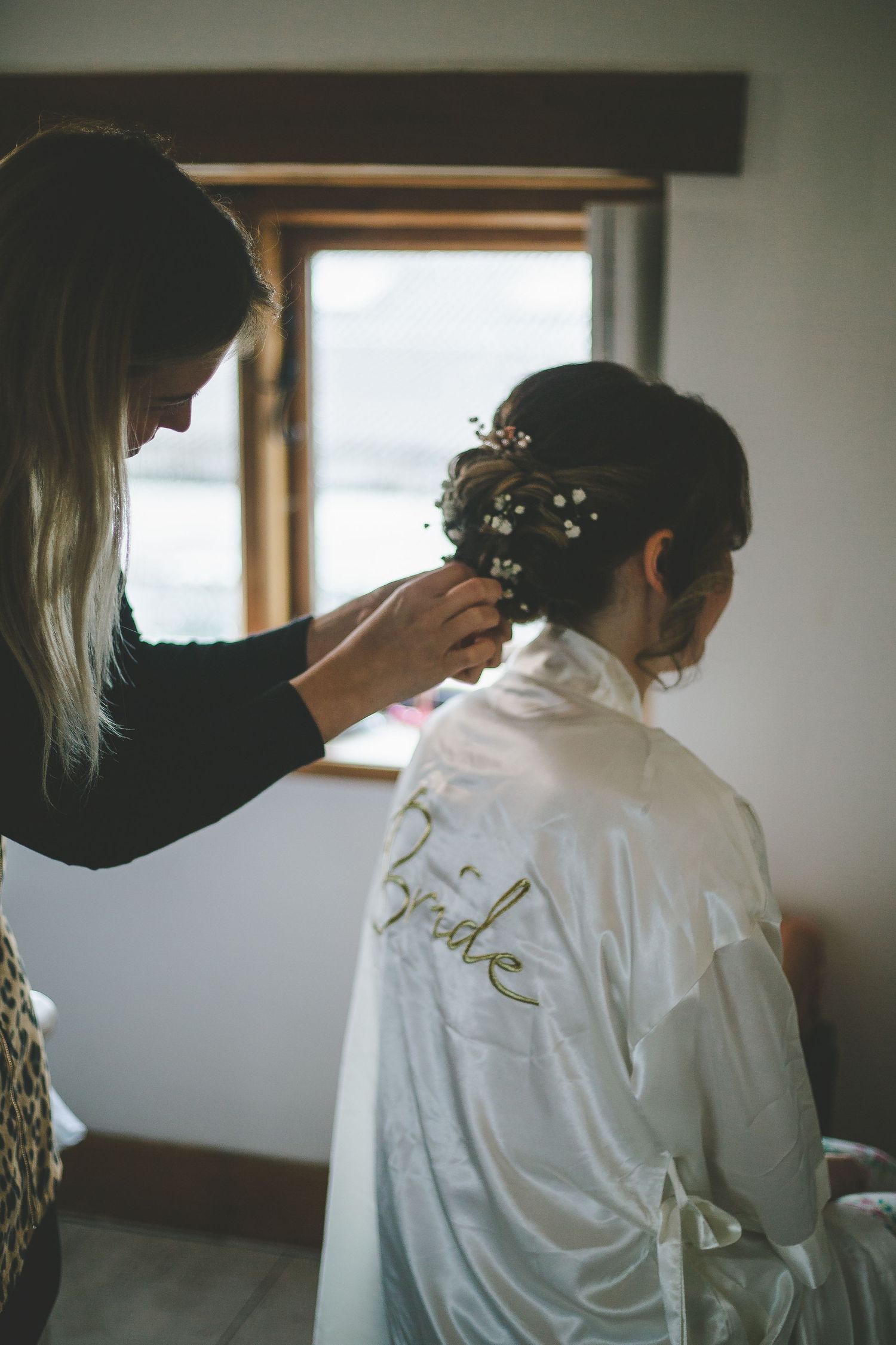 A series of photos showing someone in a white satin robe getting their hair styled from behind.