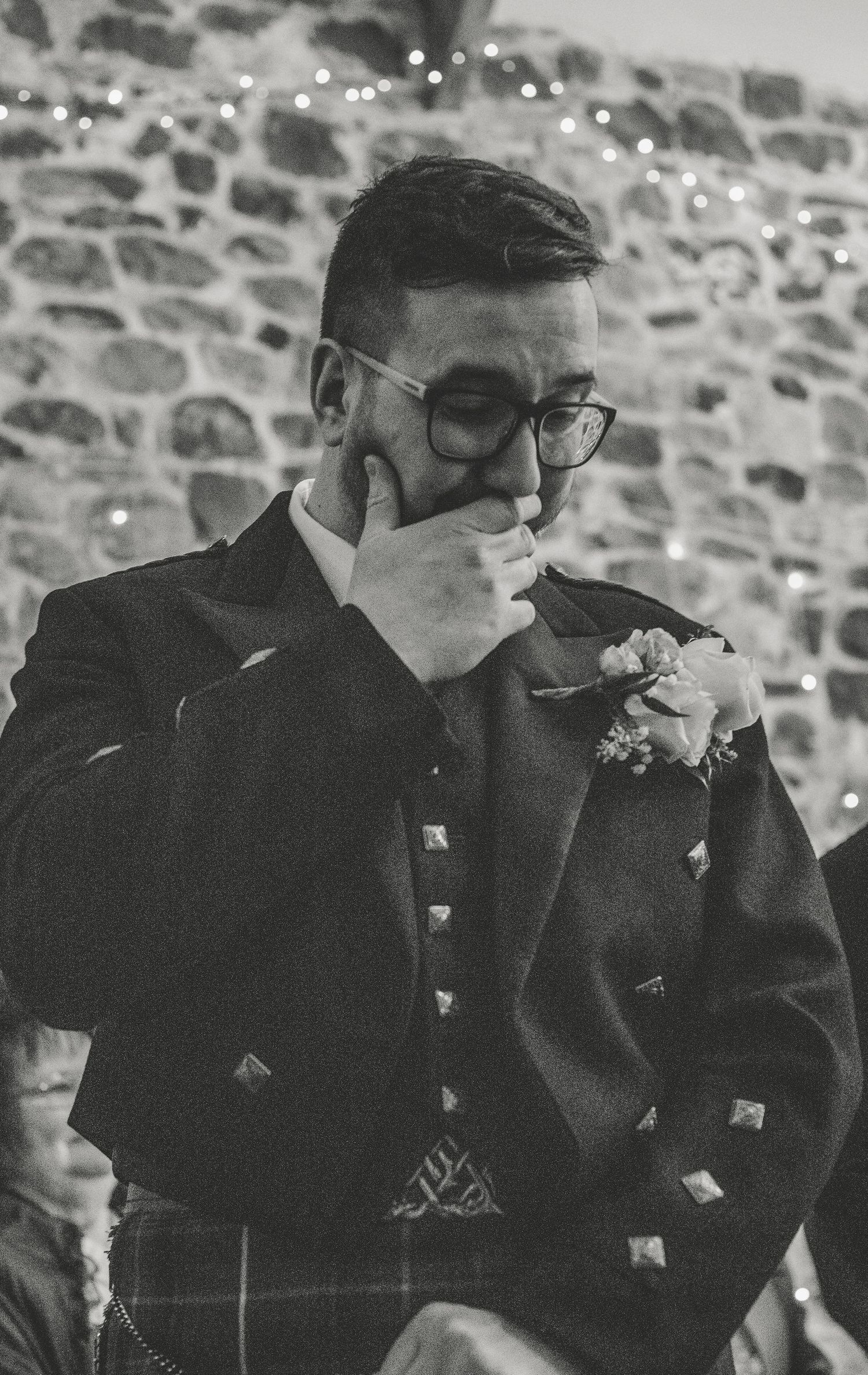 Emotional groomsmen in black suits wipe away tears during a touching wedding moment.