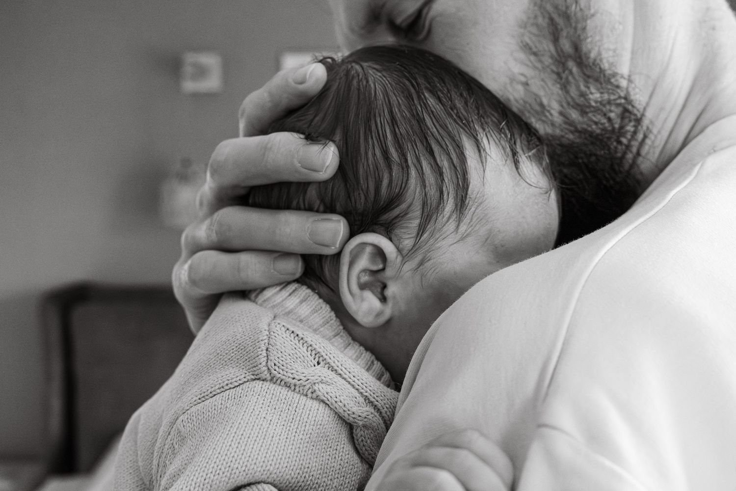 Black and white family photograph of father and baby having moment of connection during an at home session in Lincoln, UK