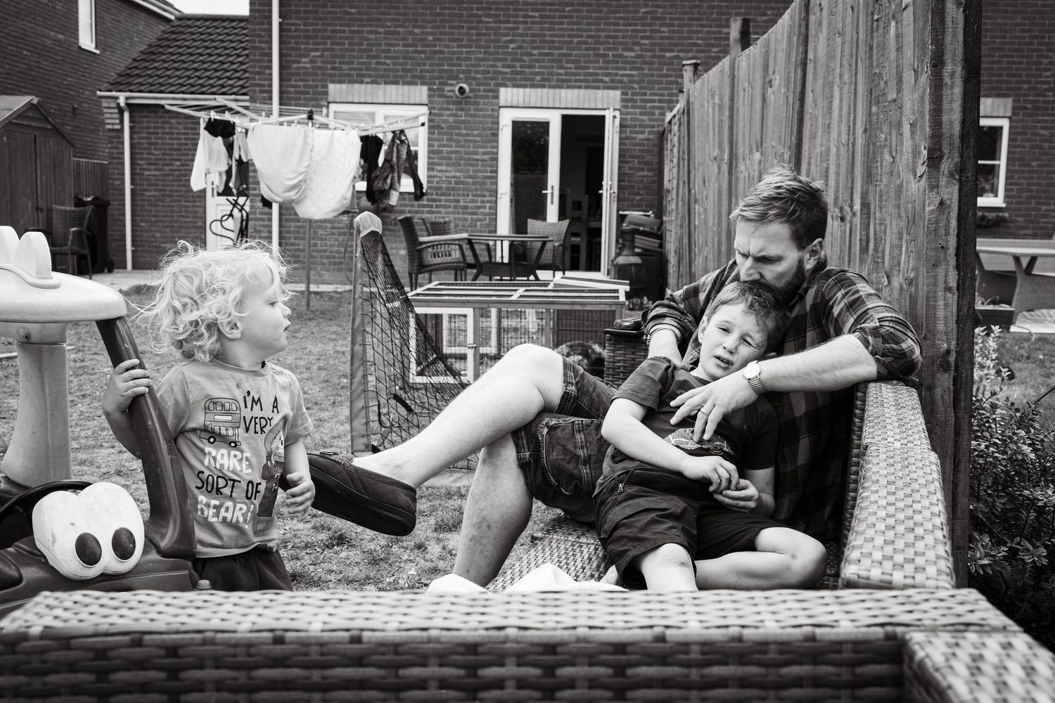Documentary family photograph in garden of home. Shows moment of connection between father and son.