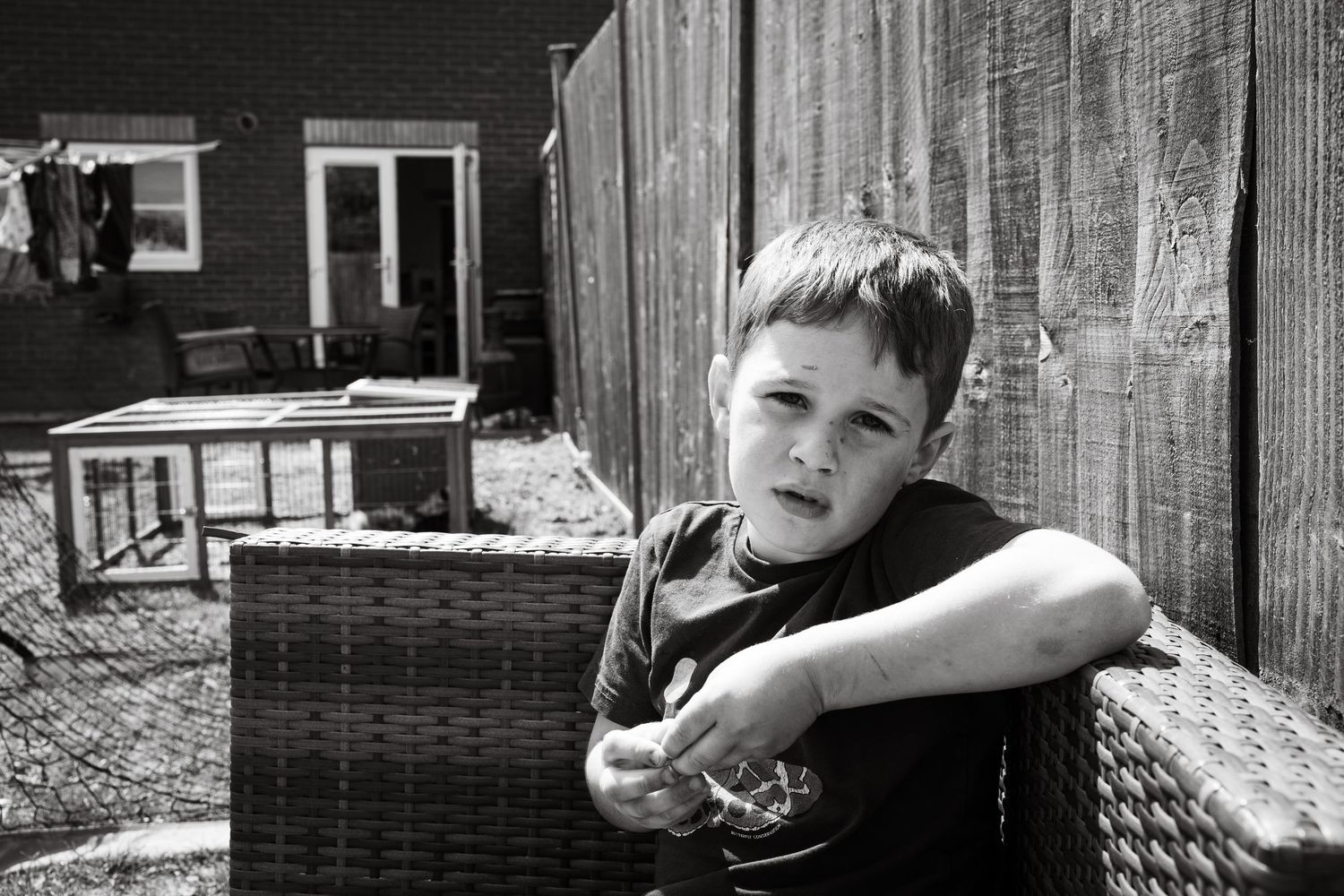 Natural documentary style family portrait in Lincoln, Lincolnshire home. Child sitting in family garden, looking at the camera.