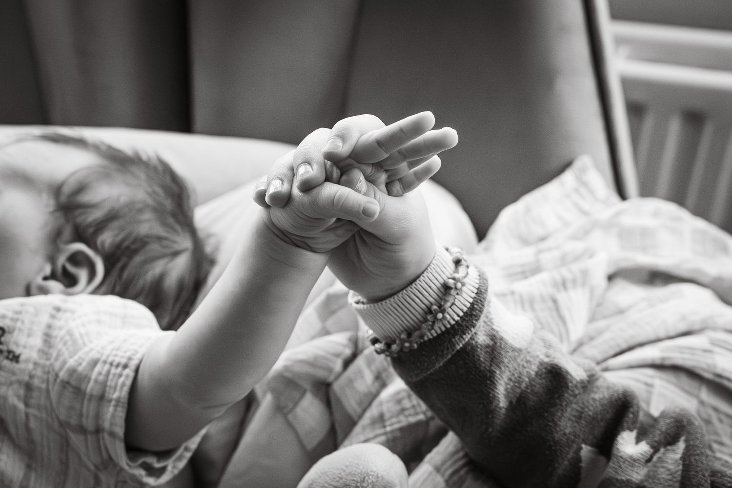 Black and white family photograph of big sister and baby having moment of connection during an at home session in Lincoln, UK