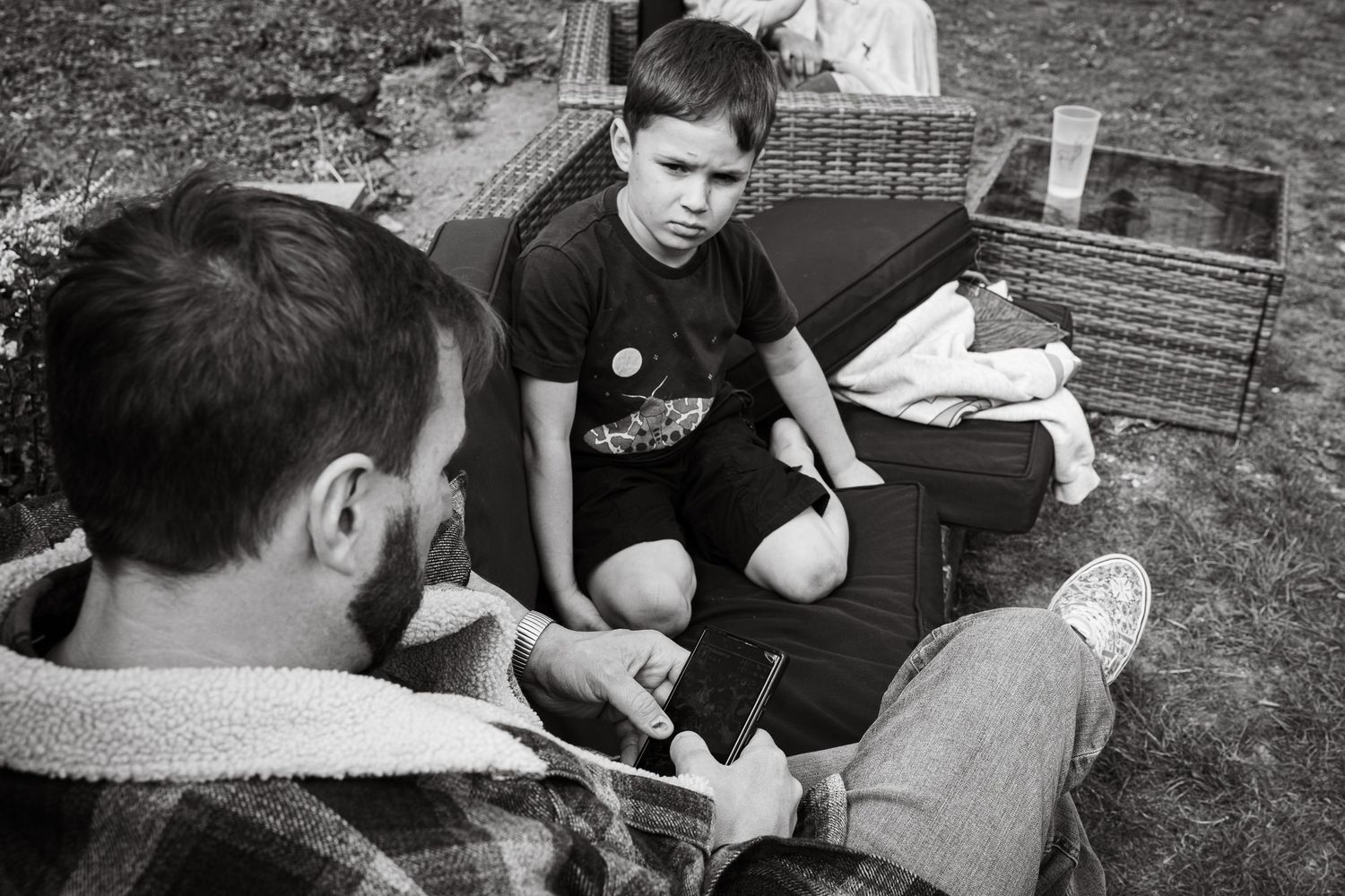 Documentary style black and white image of father and child in their back garden during an at home photoshoot capturing natural connections.