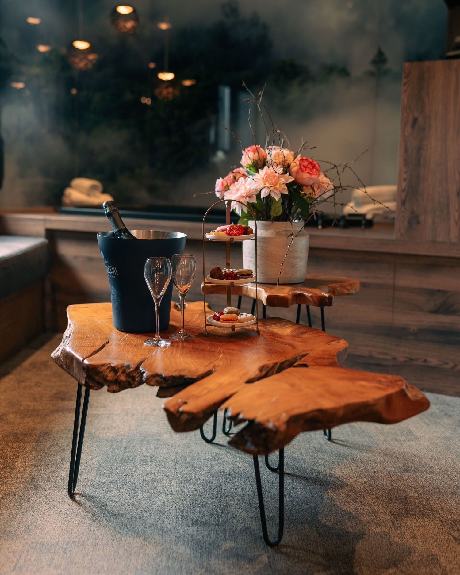 Rustic live-edge wooden coffee table with champagne, flowers, and elegant glassware in a spa lounge.