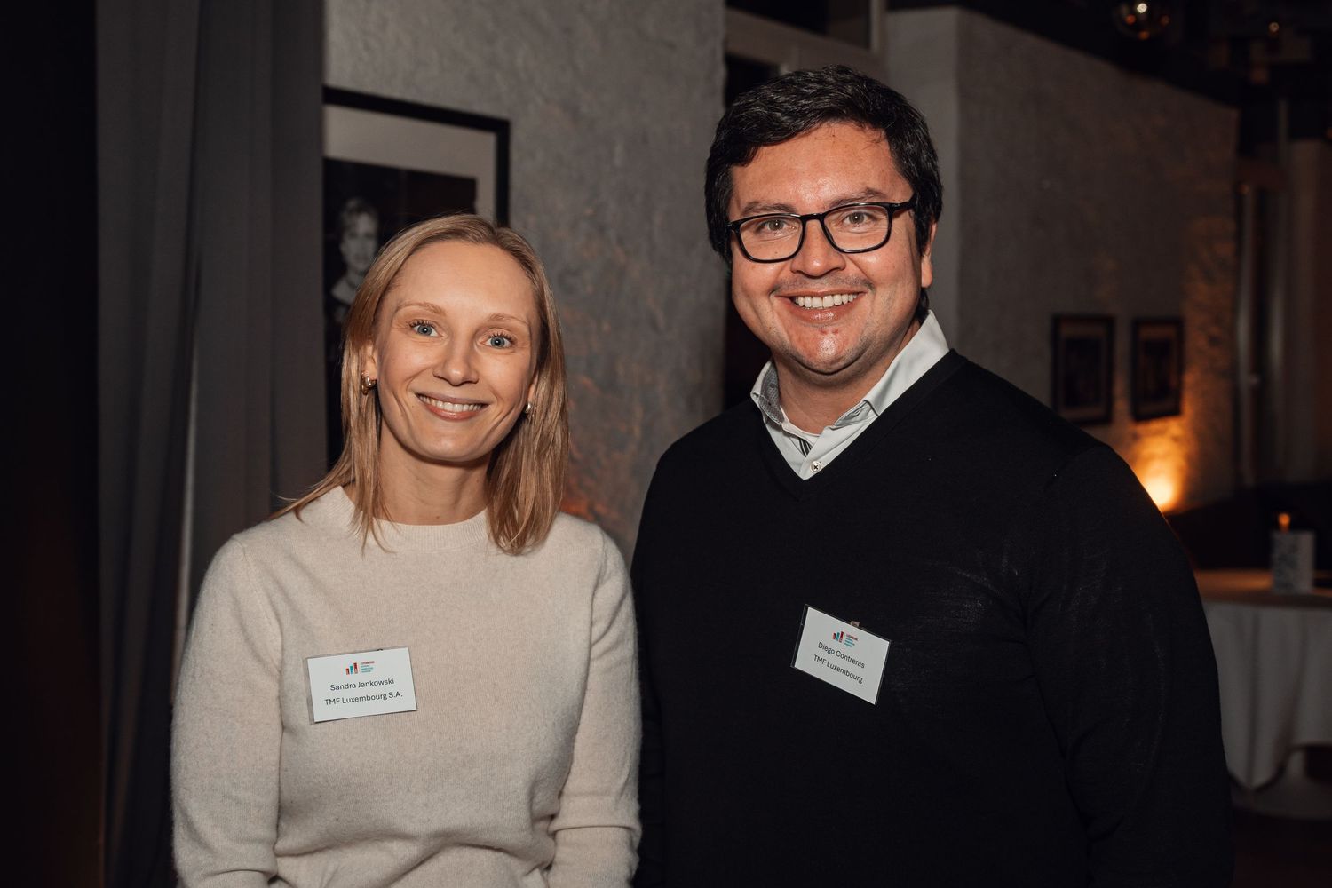 Two smiling professionals wearing name badges at a corporate networking event.