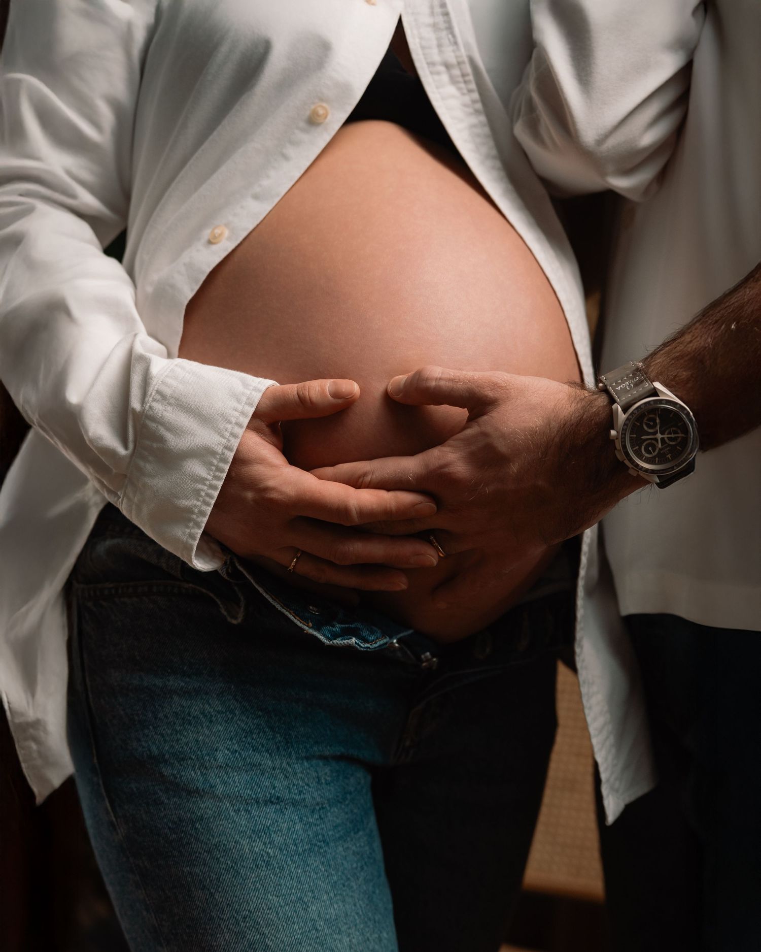 Séance photo grossesse — gros plan mains sur ventre rond en studio professionnel Luxembourg