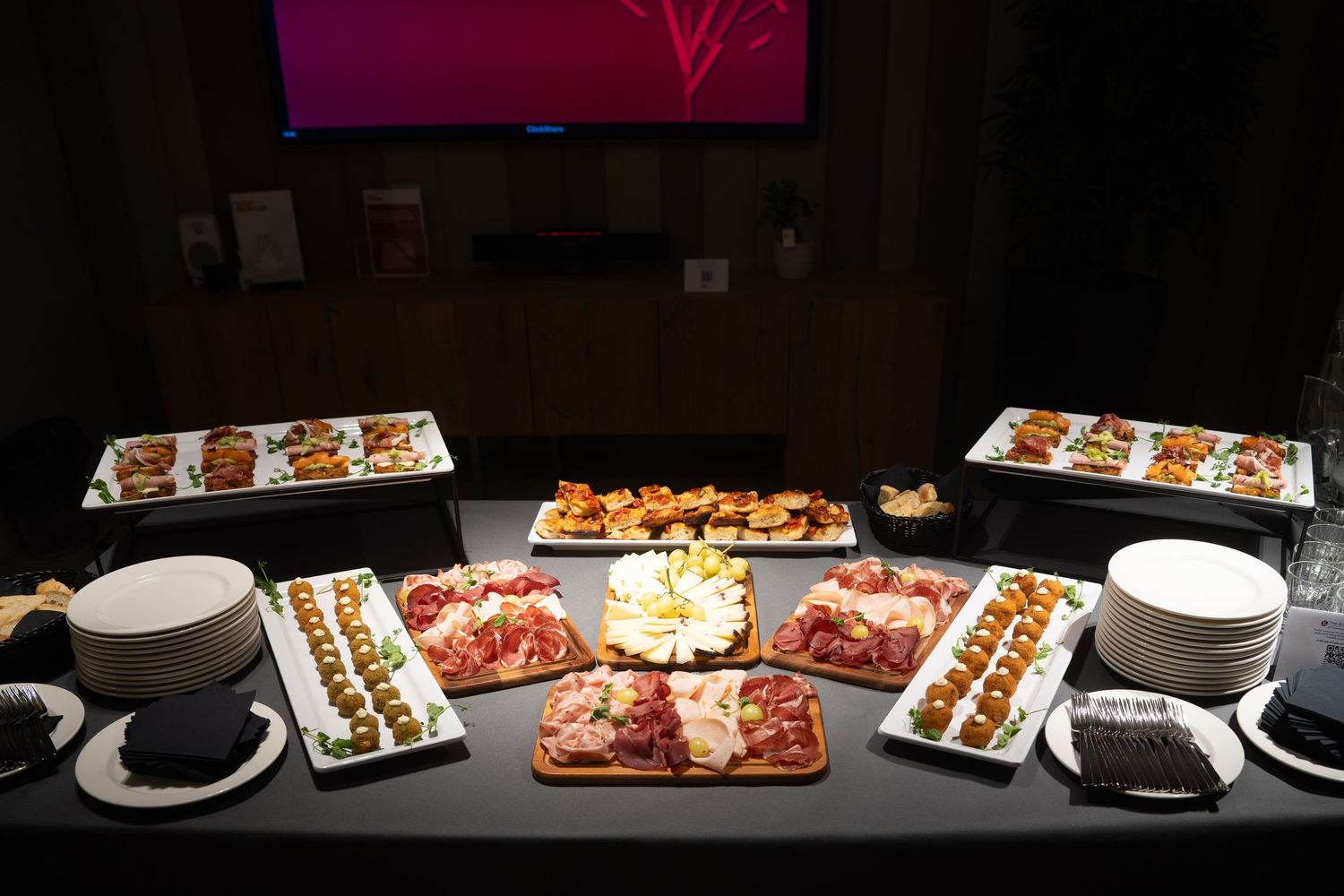 Catering buffet table with assorted appetizers, charcuterie, and finger foods at a corporate event.