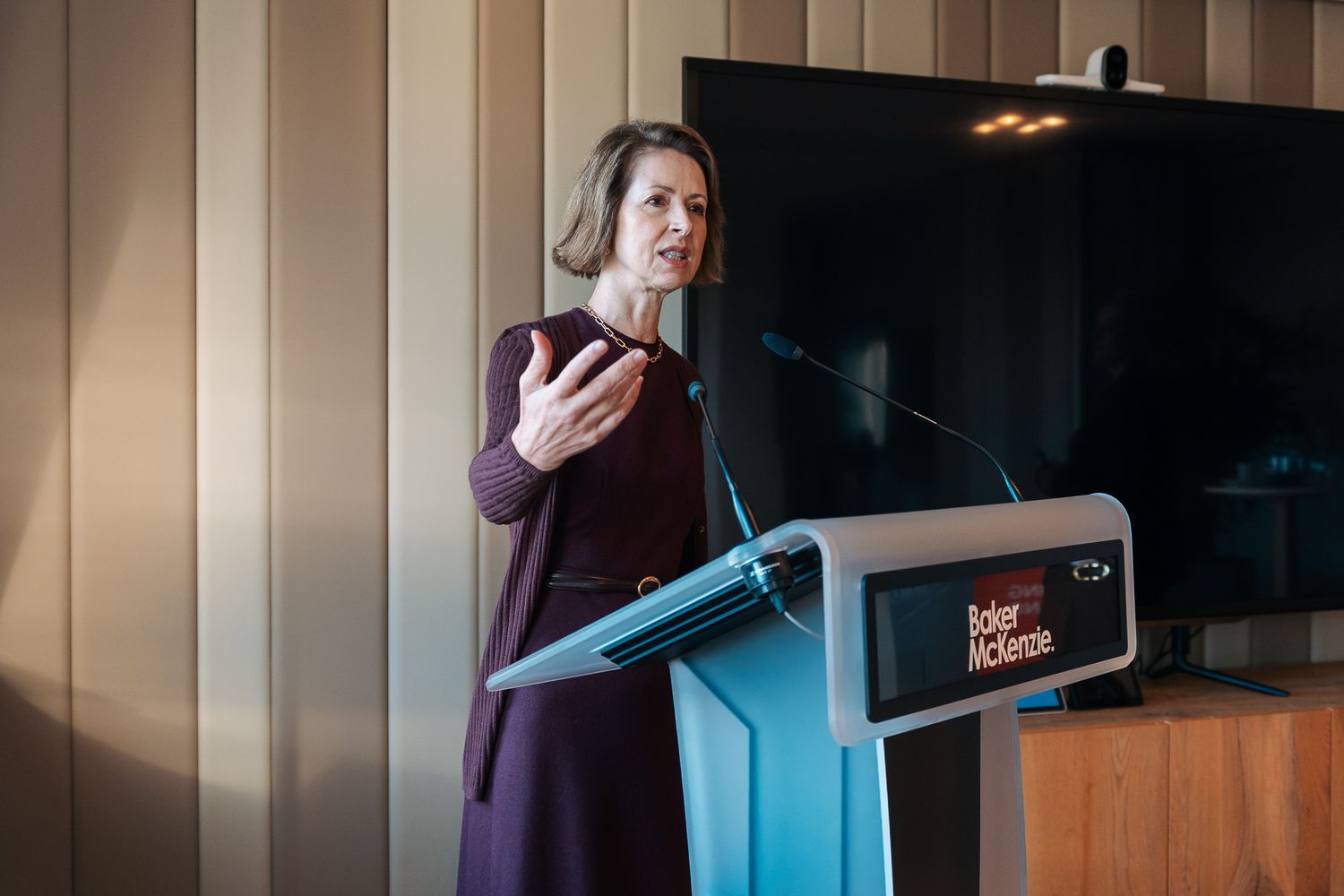 Photographie corporate — directrice présentant lors d'un événement d'entreprise avec écran Baker McKenzie