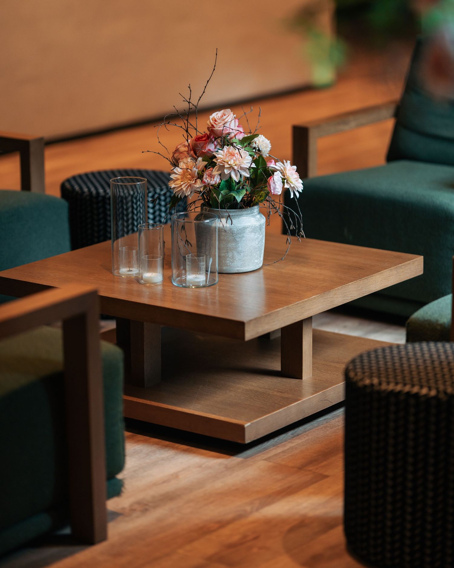 Wooden coffee table with fresh flower arrangement and glass vases in hotel lounge.