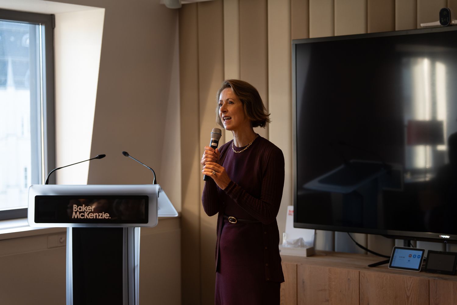 Photographe événementiel corporate — intervenante au pupitre en salle de conférence moderne Luxembourg