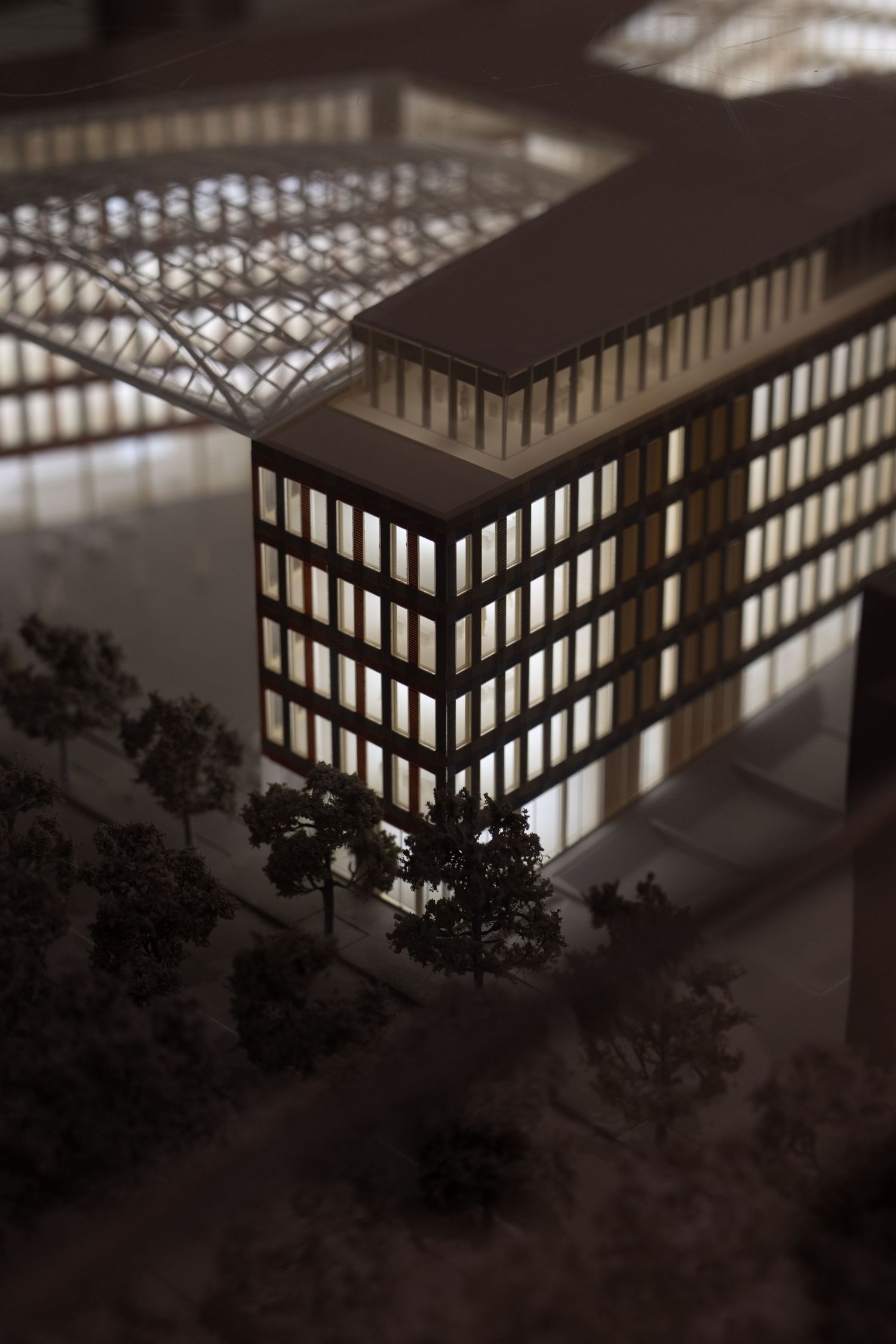 Illuminated architectural scale model of a modern multi-story office building at night.