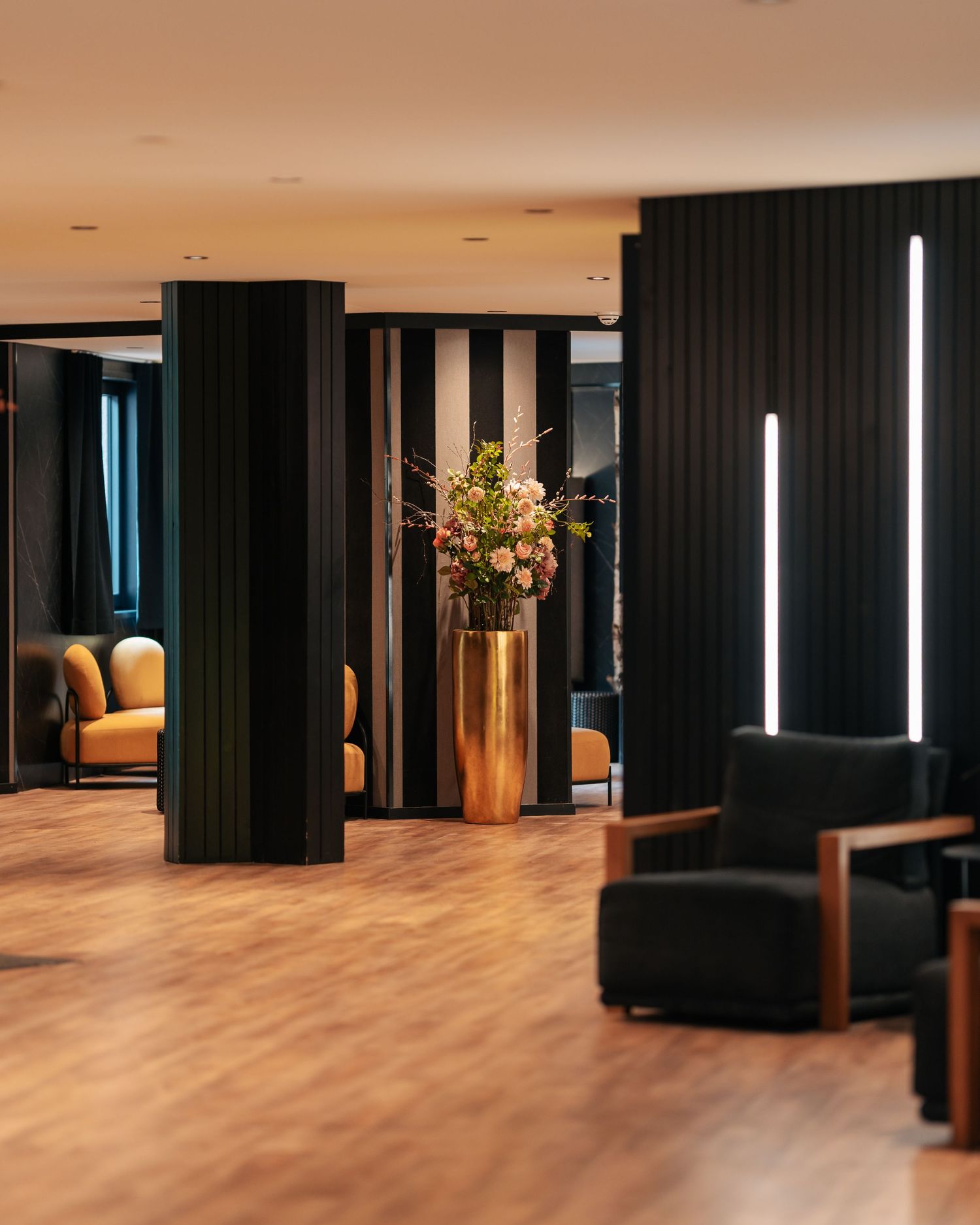 Modern hotel lobby with dark fluted columns, warm lighting, and floral arrangement.