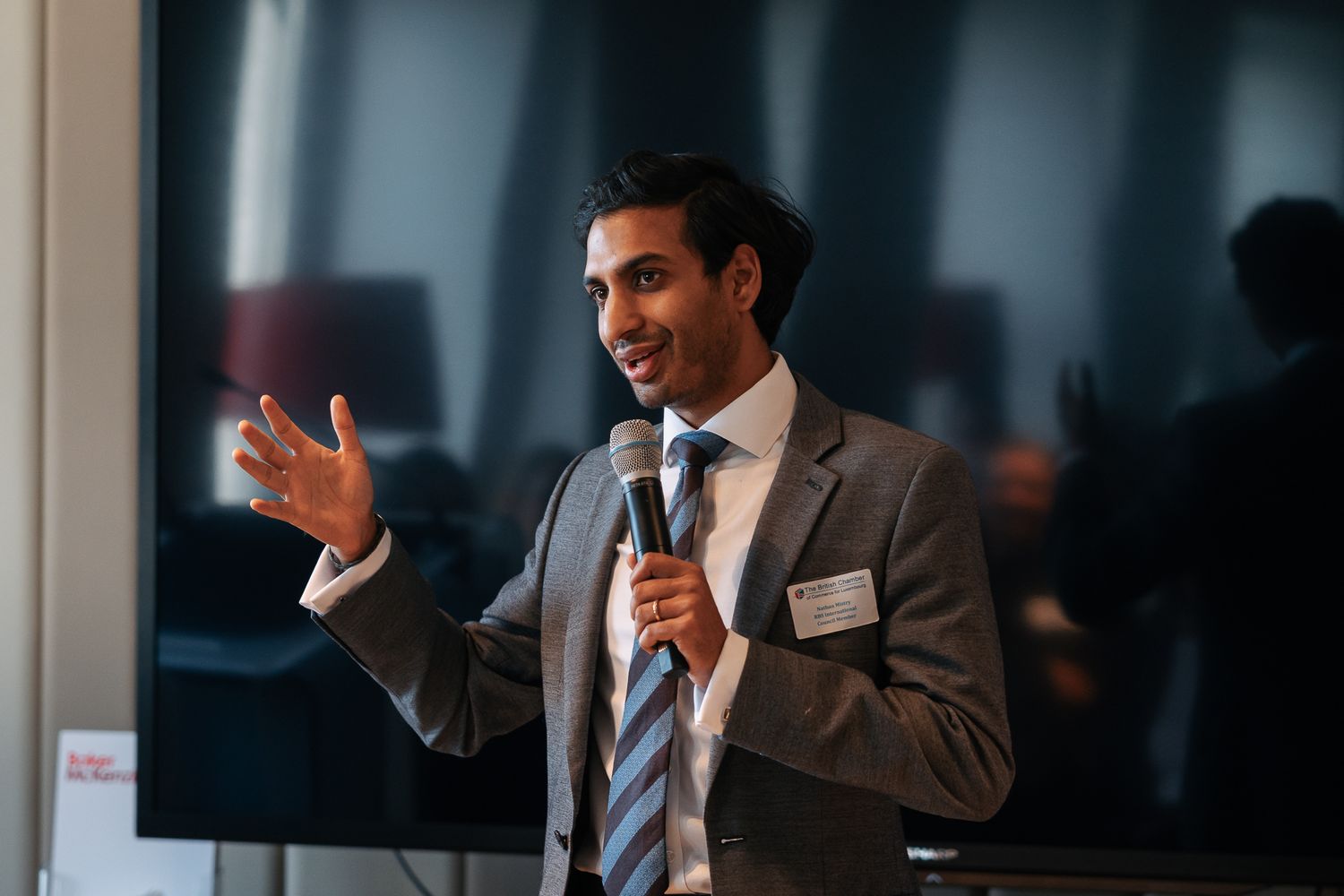 Photographie événementielle corporate — intervenant masculin au microphone lors d'une conférence professionnelle Baker McKenzie