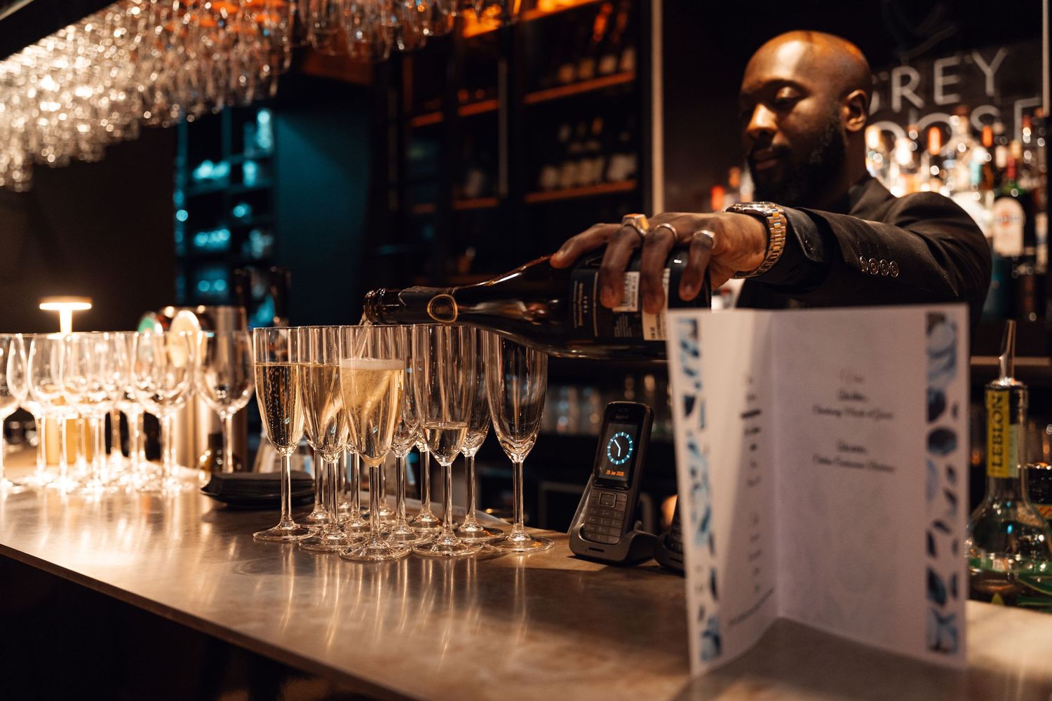 Bartender pouring champagne into glasses at an elegant corporate event bar.