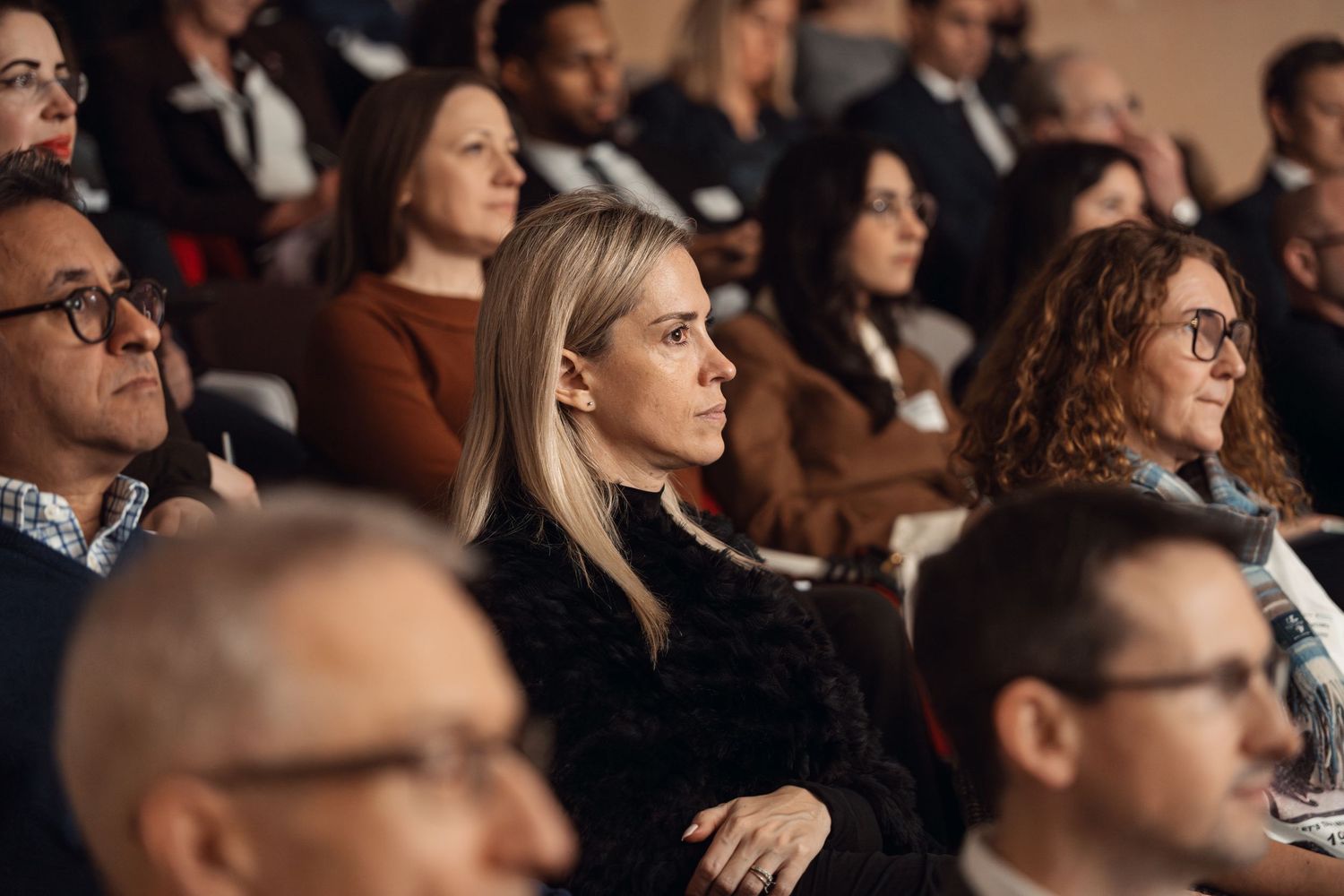 Audience of professionals attentively listening at a corporate conference event.