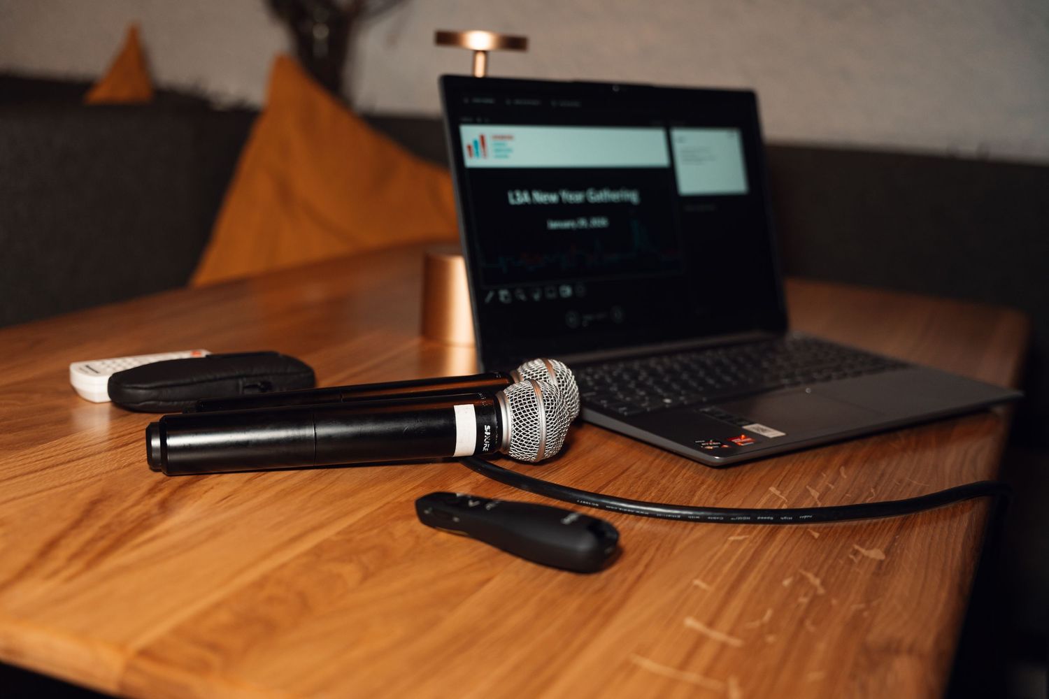 Microphone and laptop displaying LBA New Year Gathering presentation on wooden table.