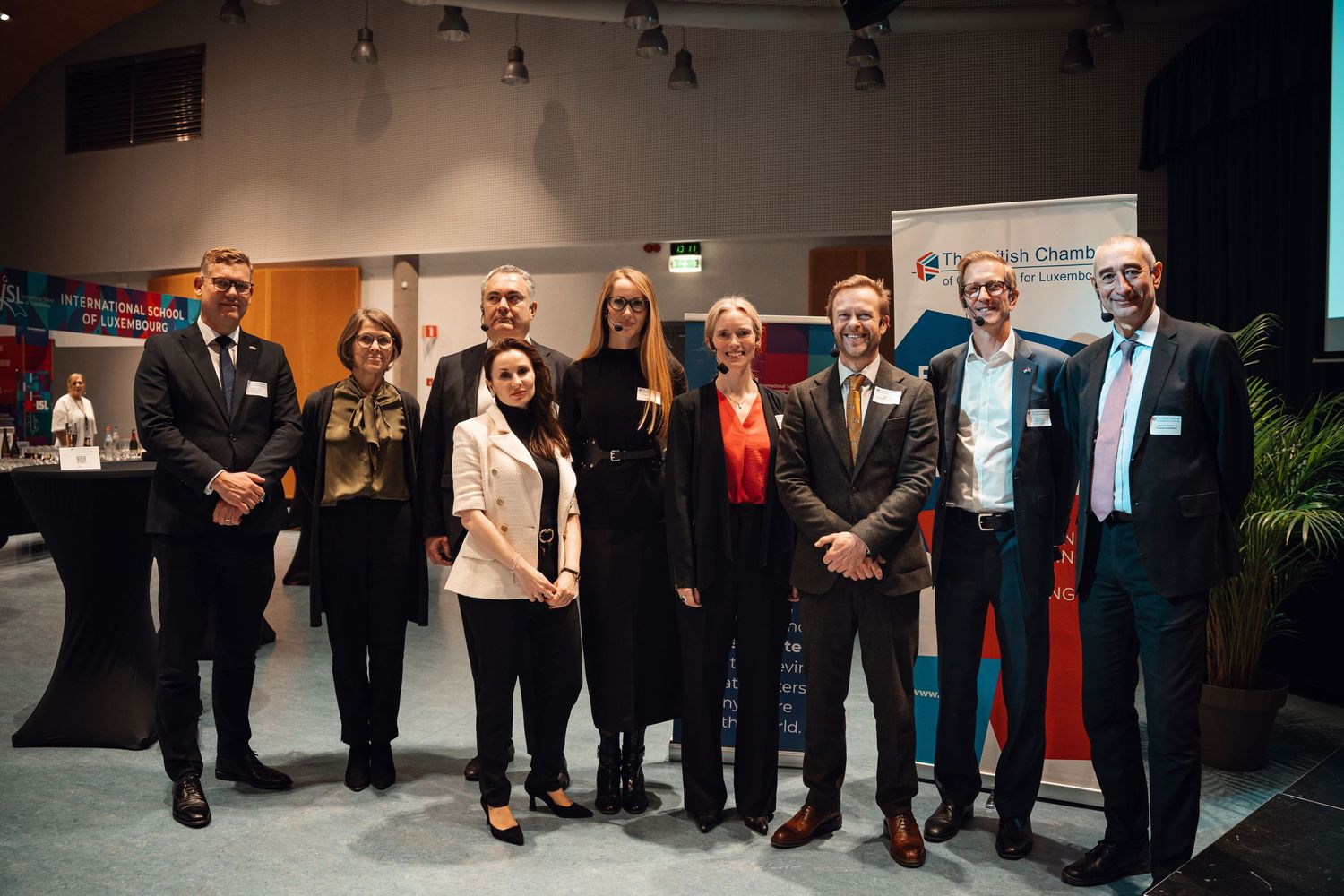 Group of business professionals posing together at corporate networking event with branded banner.