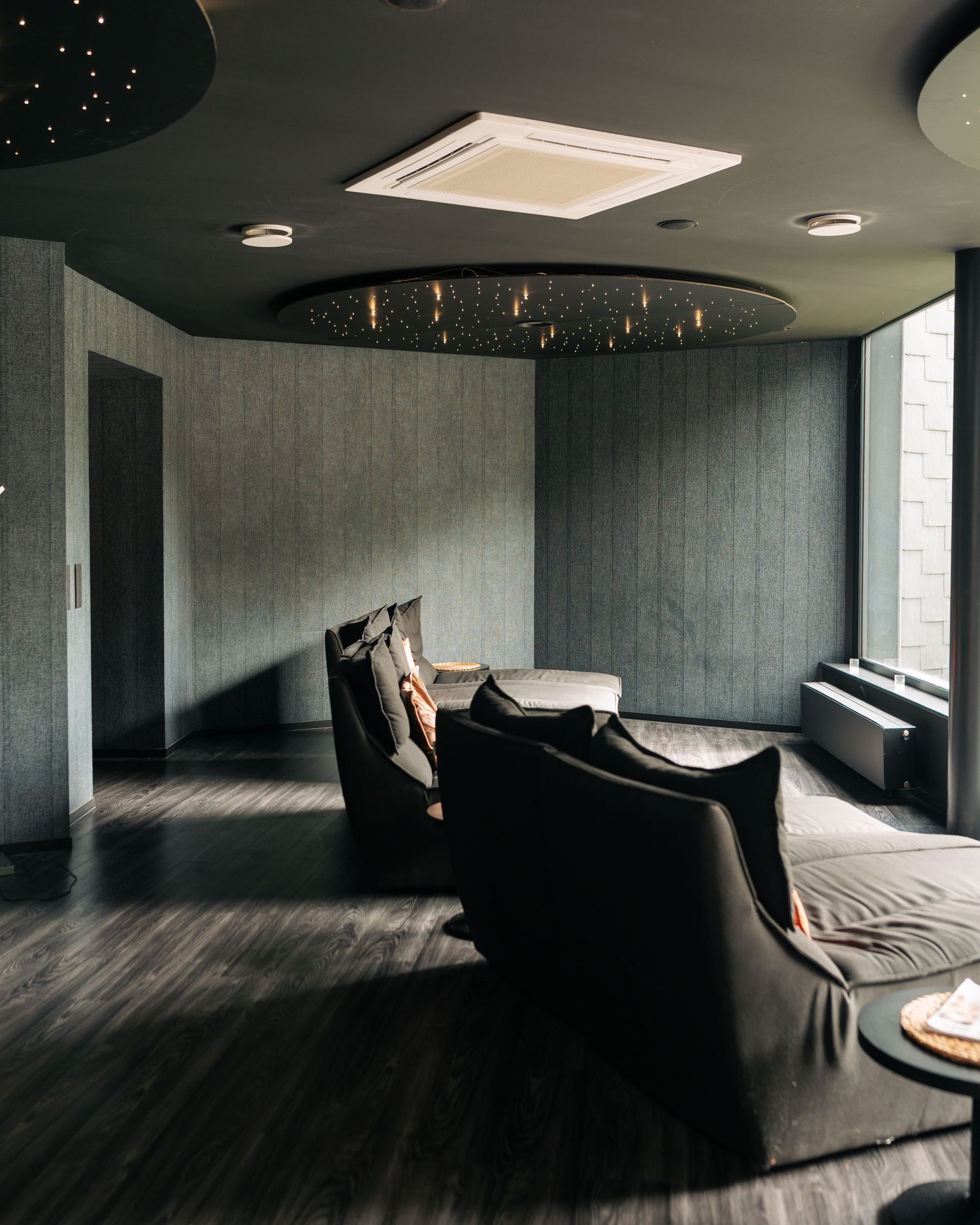 Dark luxury spa relaxation room with reclining chairs and starlight ceiling decor.