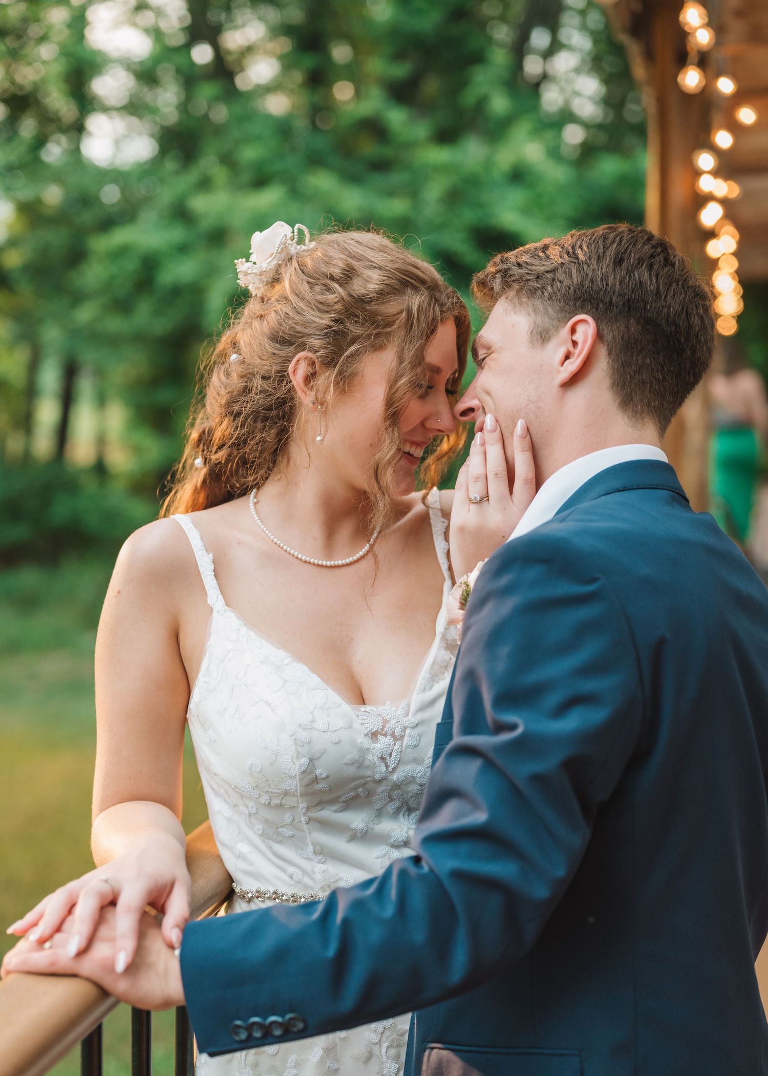 A romantic moment between newlyweds against a backdrop of trees and string lights.