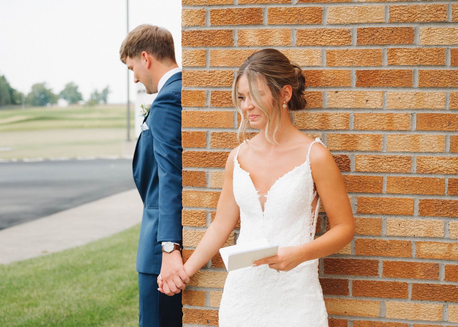 A couple shares a romantic moment in front of a brick wall during their outdoor wedding photo session.