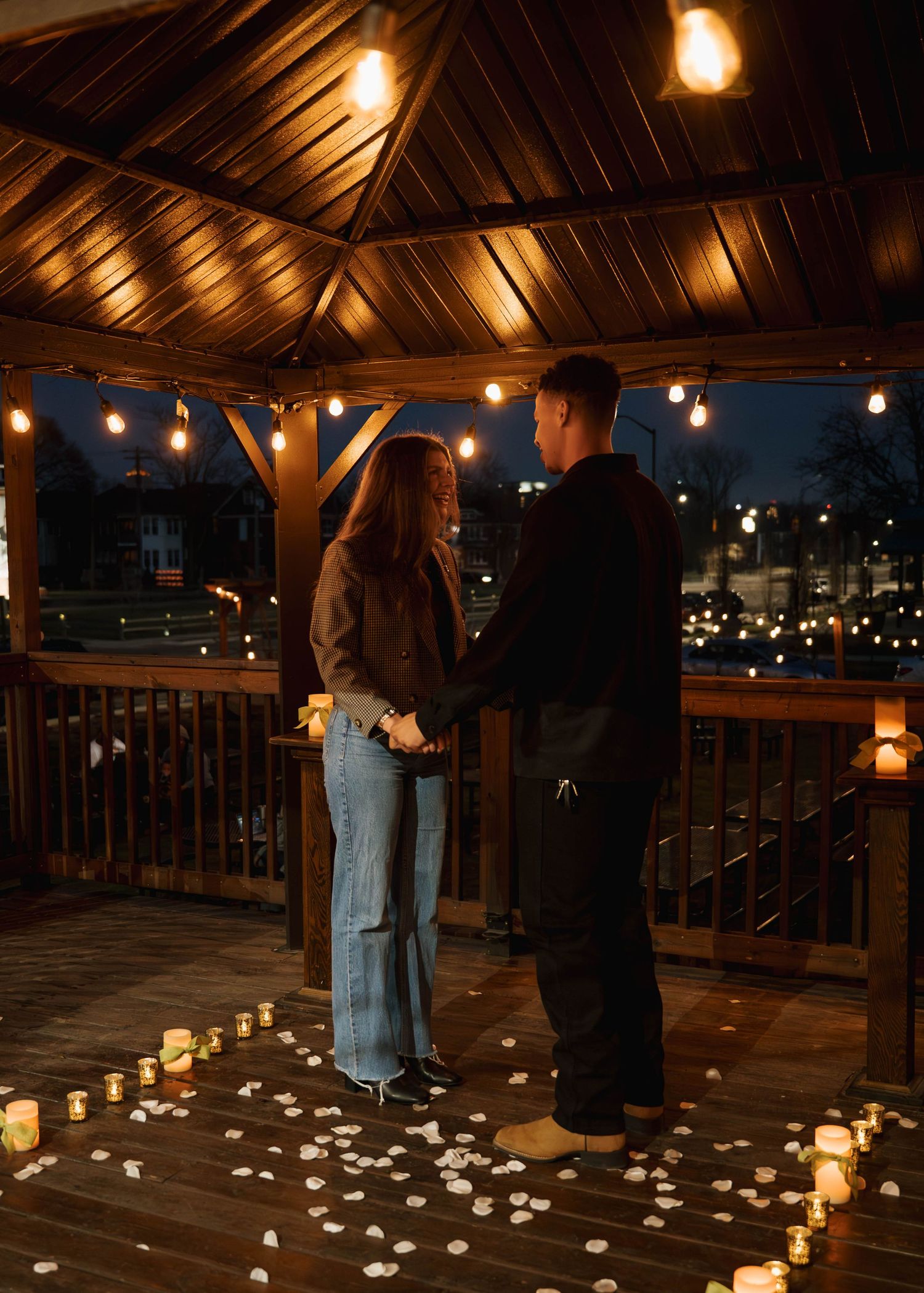 Romantic scene on a wooden deck with string lights and candles creating a warm ambiance.