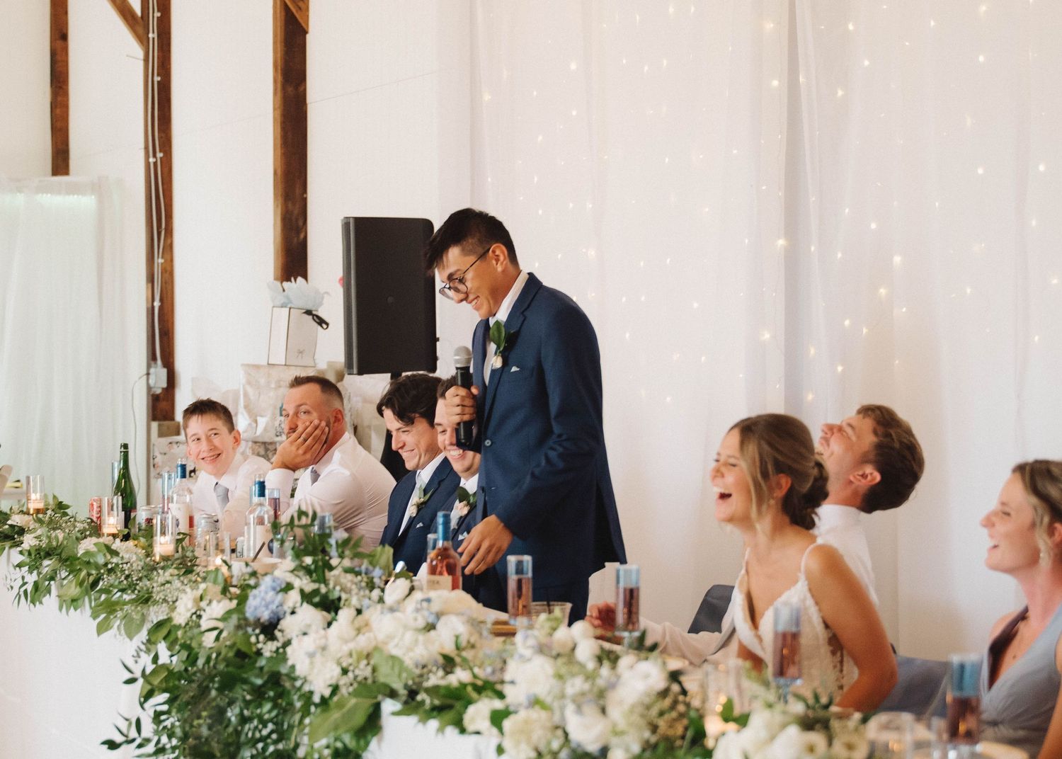 Wedding reception table decorated with elegant white floral arrangements and glowing candles.