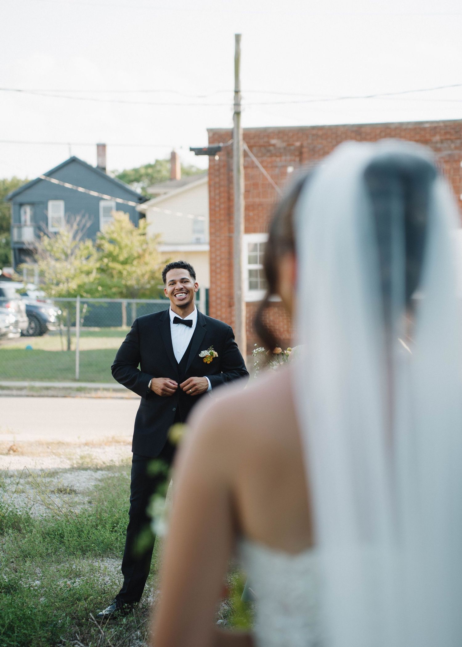 A first look wedding moment between a couple outdoors with brick buildings in the background.