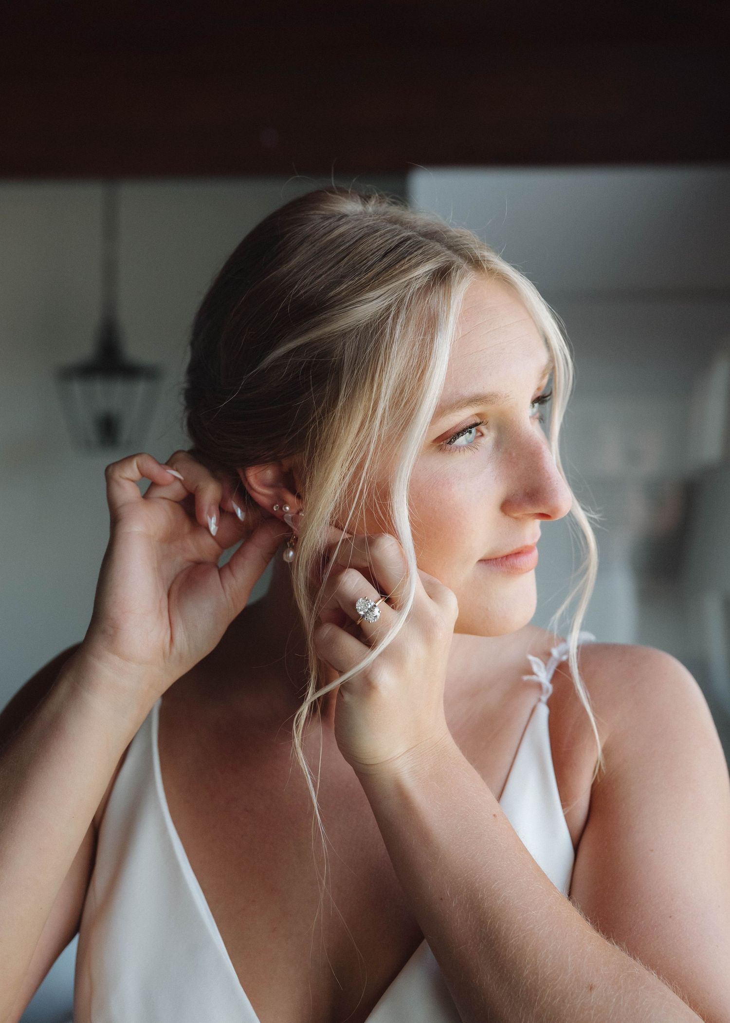 A series of close-up shots showing someone putting on earrings in a white top against a light background.