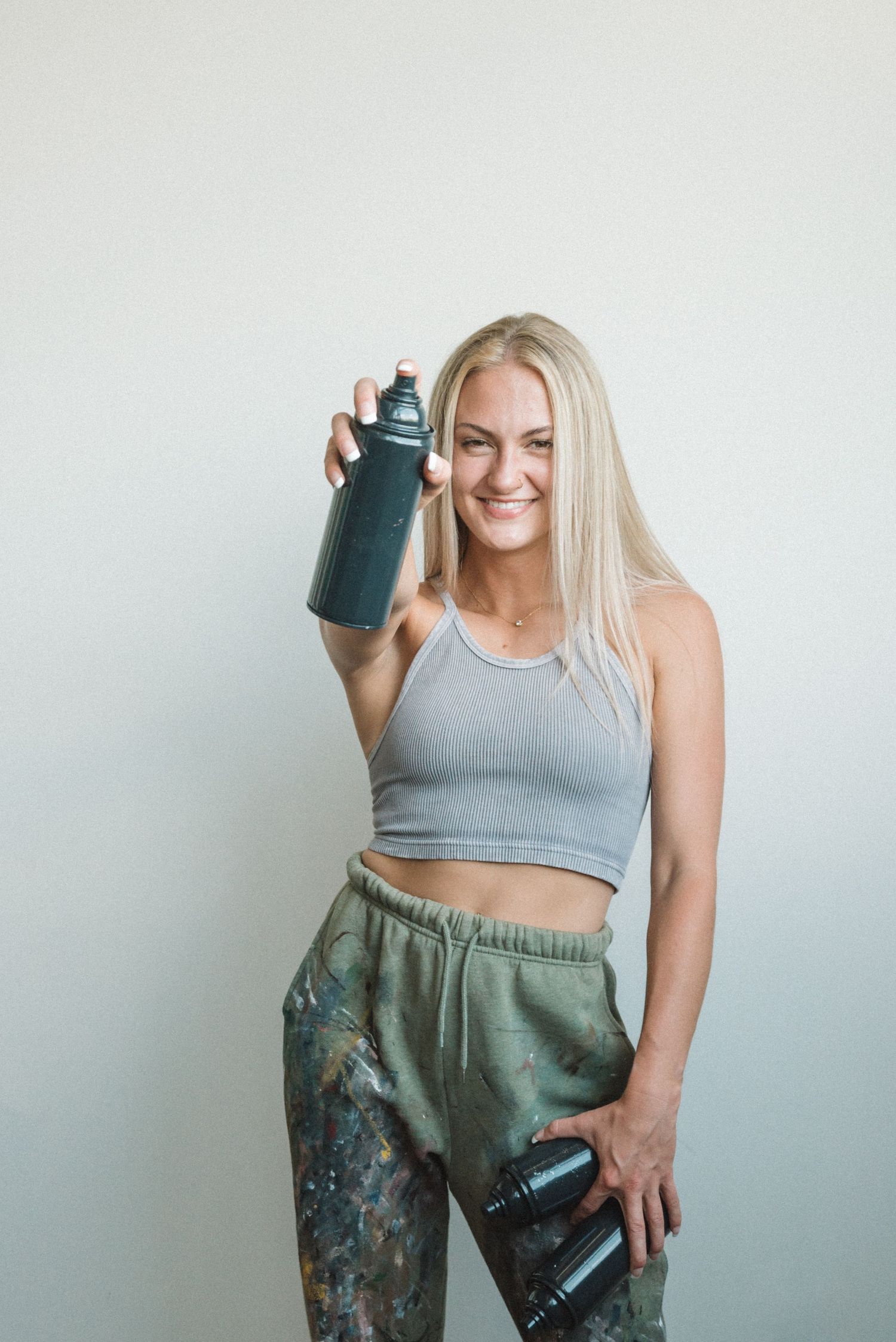 Person in athletic wear holding water bottle against minimal white background.