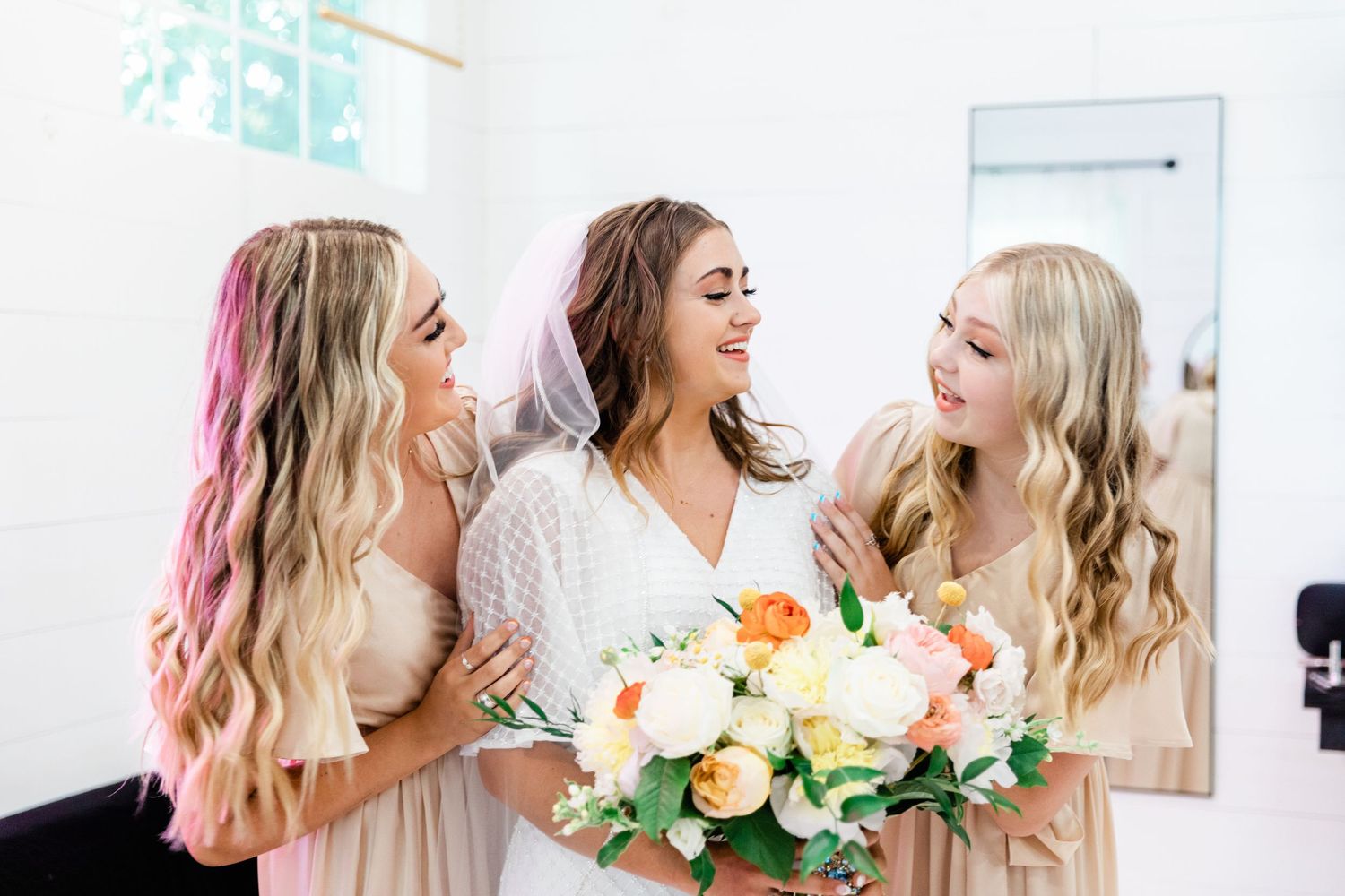 Bride and her bridesmaid sharing a laugh while getting ready for the wedding.