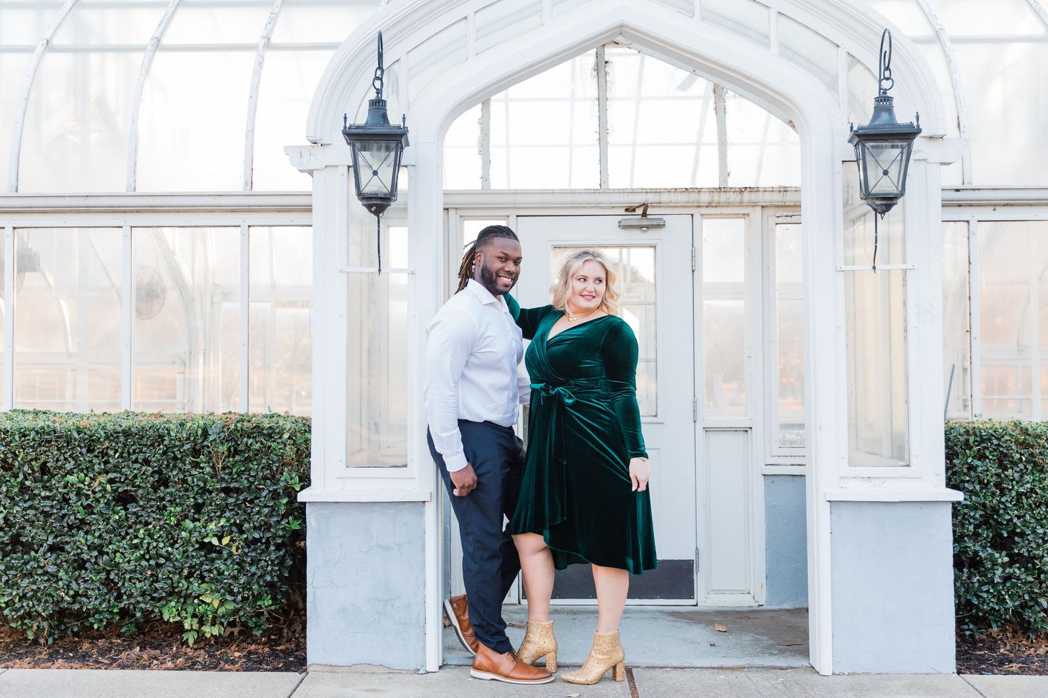 Full body shot of the bride and groom in front of the Texas Women's University greenhouse for their engagement session.