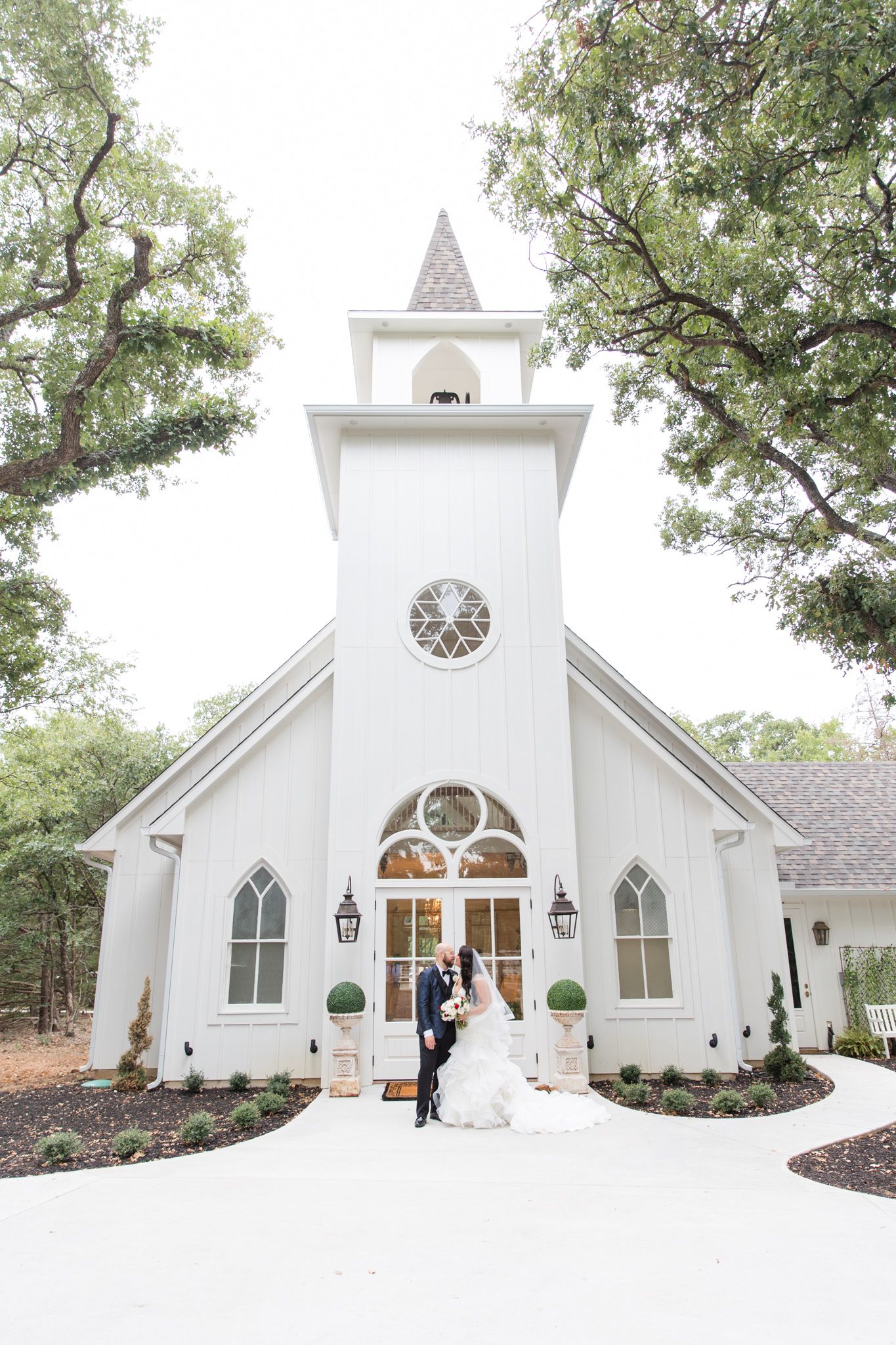 Bride and groom sharing a kiss in front of the ornated doors of the chapel at the French Farmhouse.