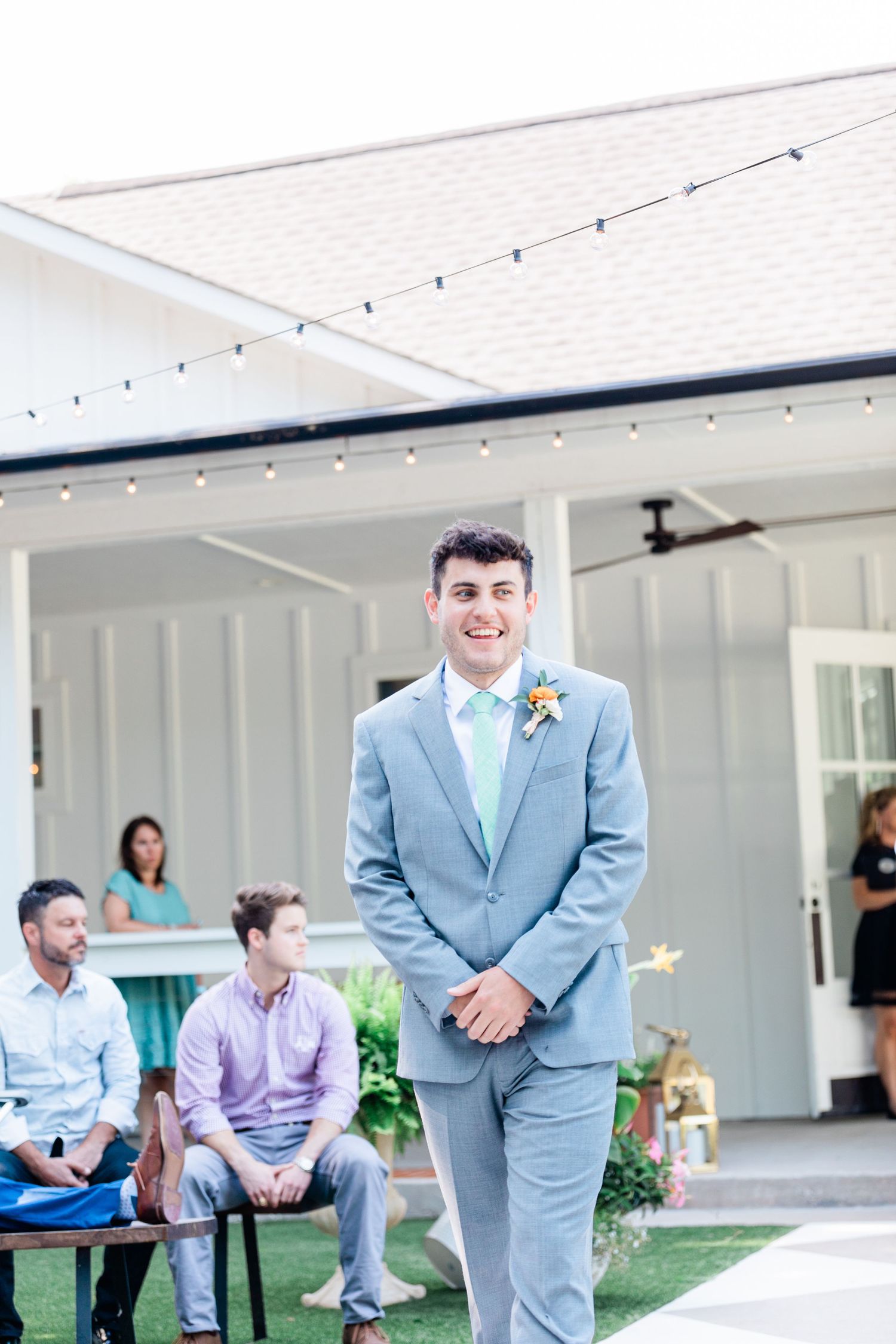 Groom walking down the aisle during the processional for an outside ceremony at The RsoeMary Barn in McKinney Texas.