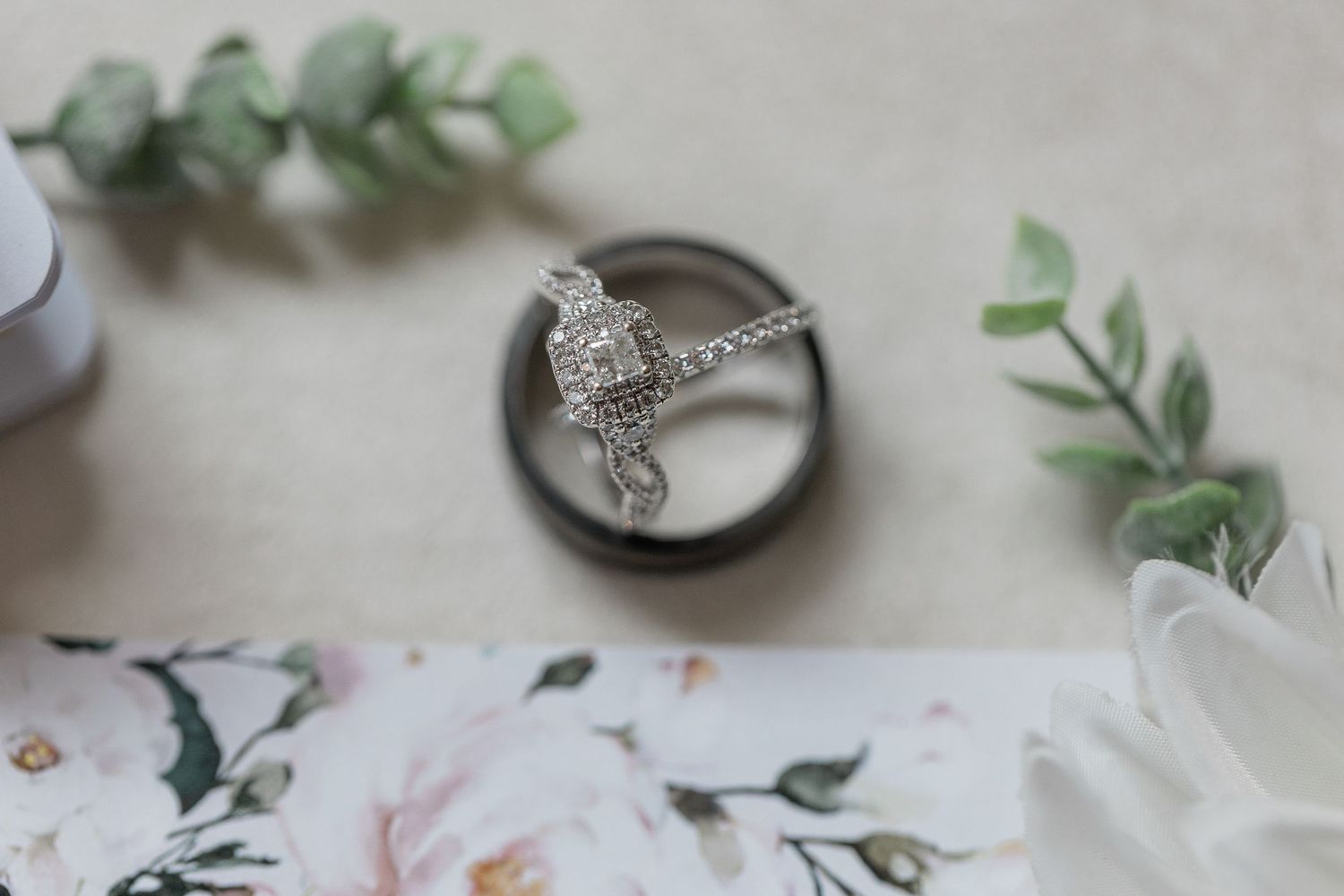 His and hers rings nested together next to their wedding invitations.