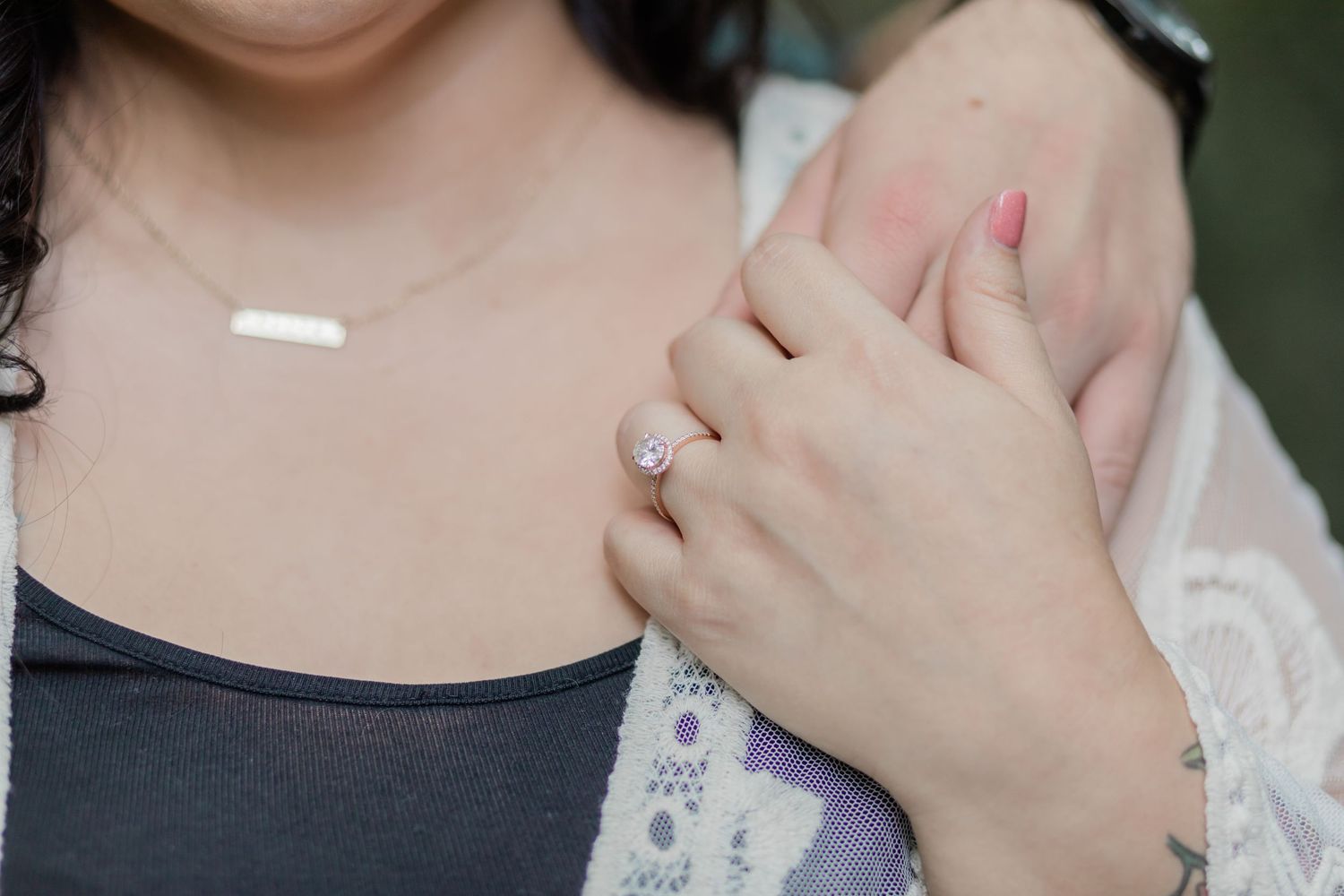close-up of the diamond solitaire ring on the bride's hand laced with the grooms during their engagement session.